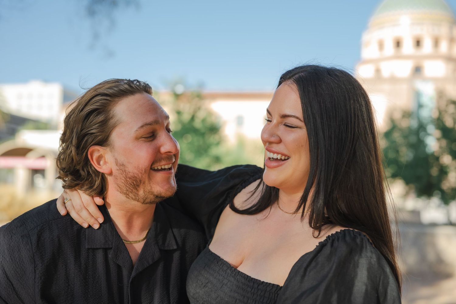 A joyful moment shared outdoors with a domed building visible in the background.
