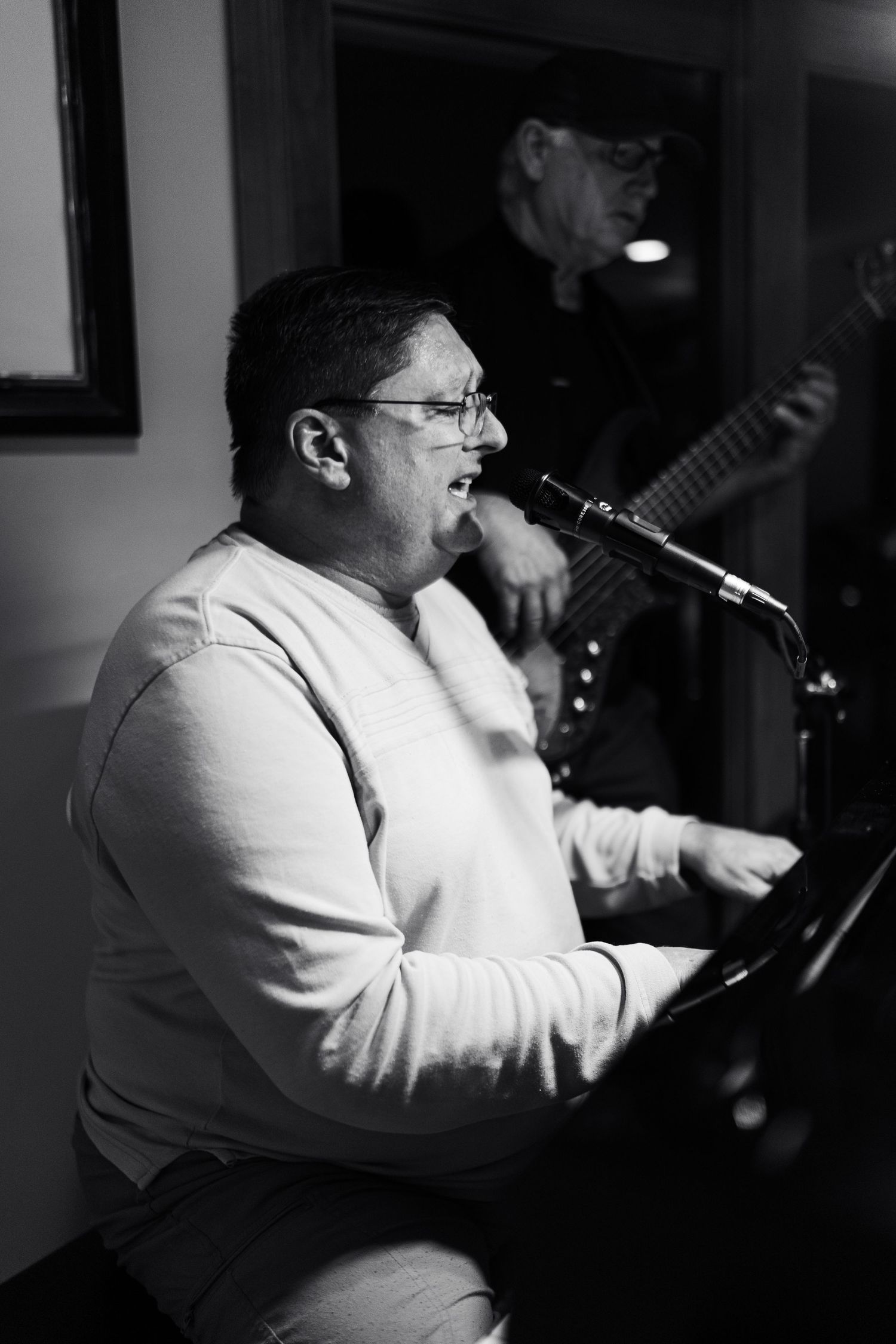 Black and white photos of a performer singing passionately into a microphone during a musical performance.