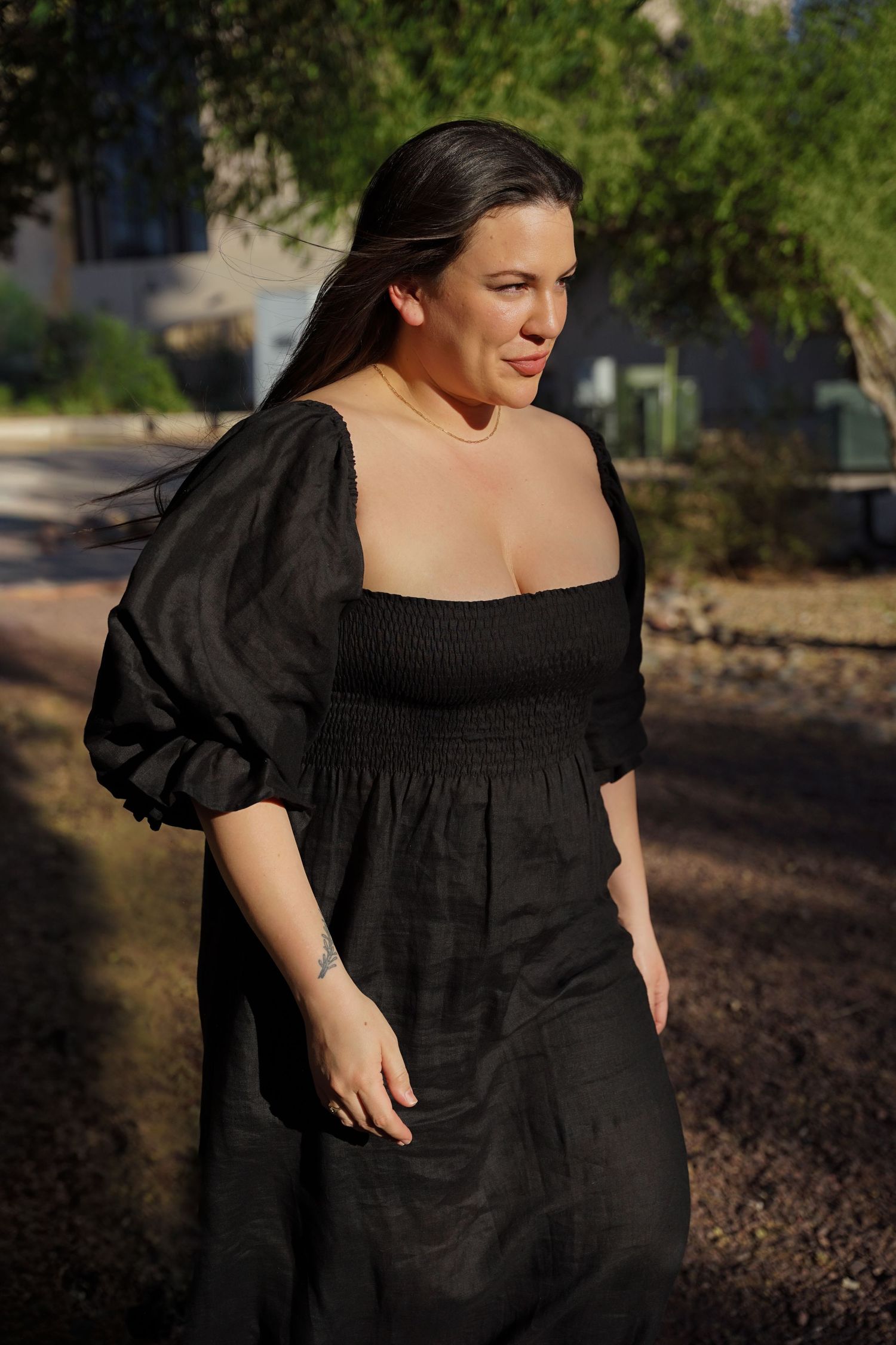 A black dress with puff sleeves photographed outdoors in natural sunlight.