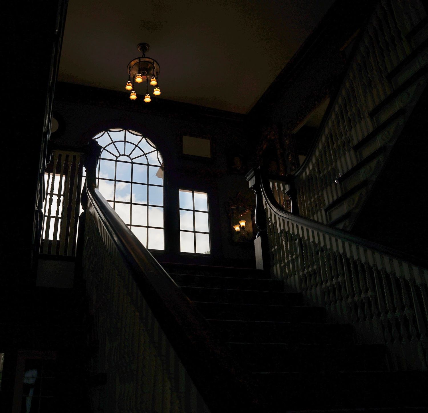 Dark interior staircase with dramatic window lighting and architectural details.
