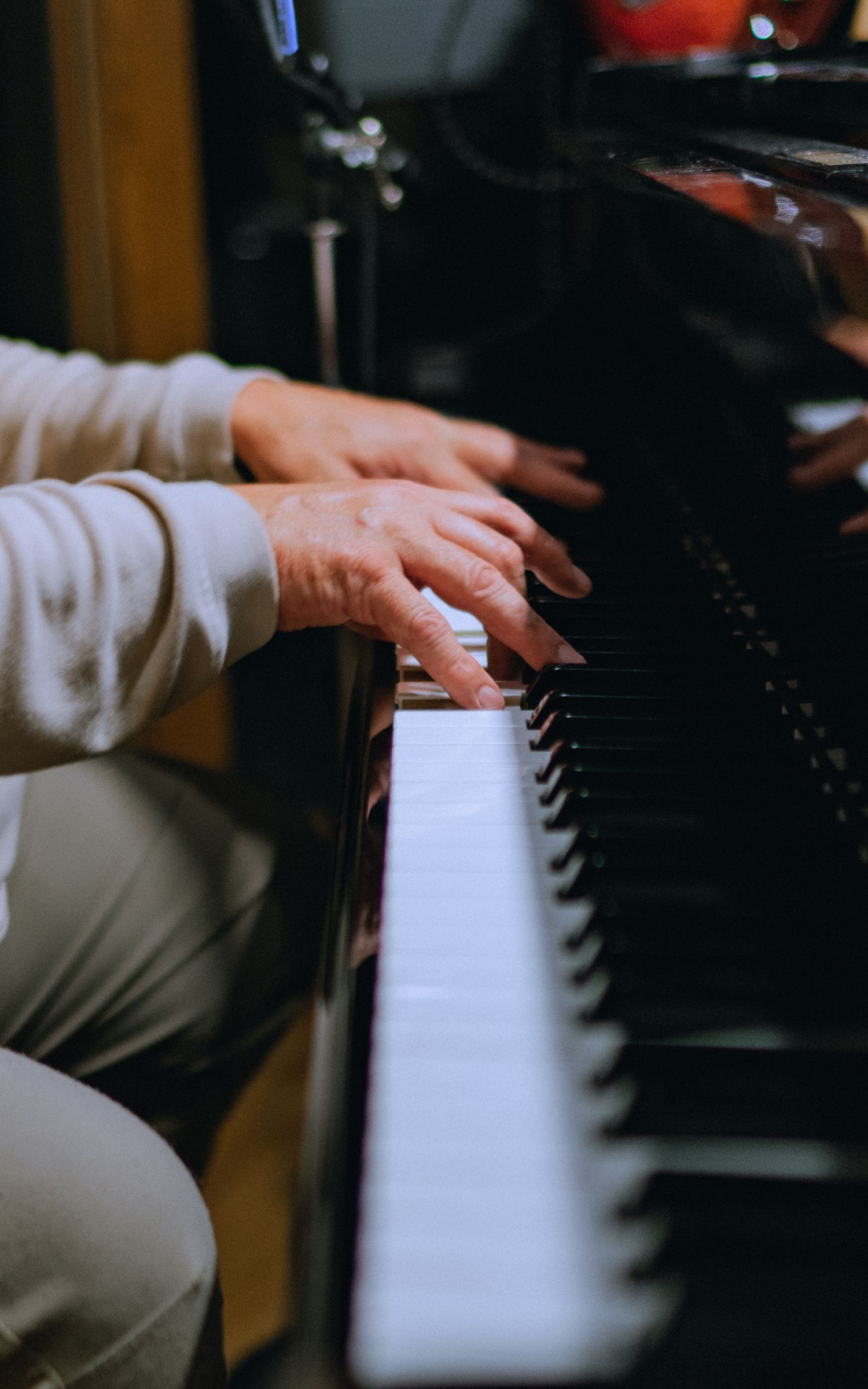 Close-up shot of hands playing piano keys in dramatic lighting.