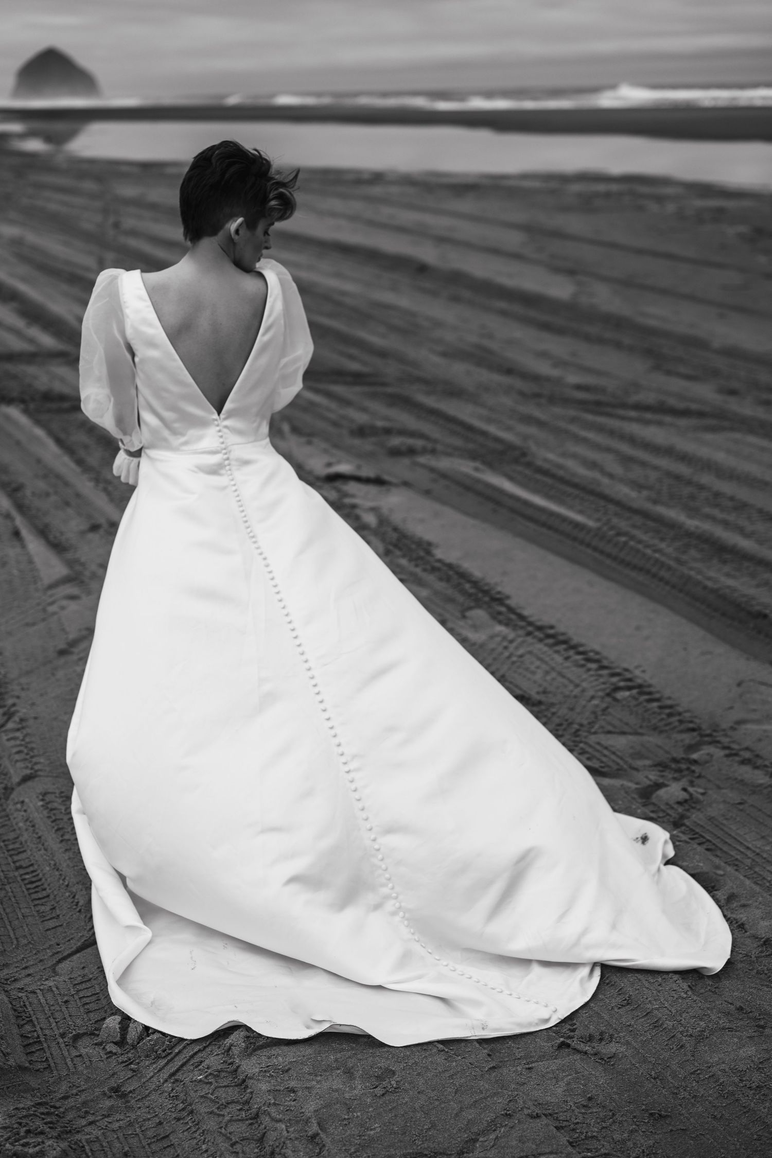 Wedding dress photographed on beach sand with intricate button details down the back.