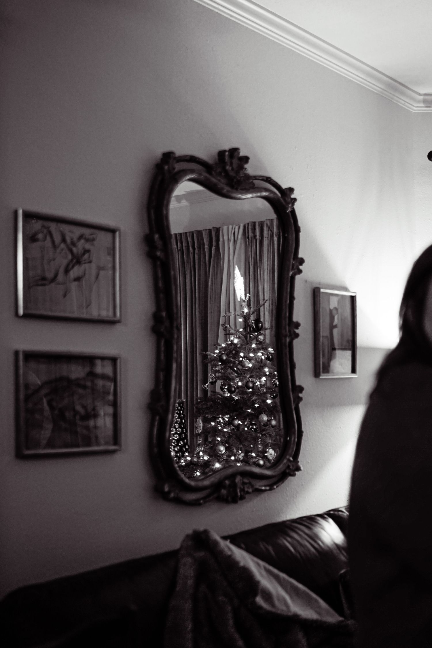 A dimly lit room with ornate mirrors and a Christmas tree reflecting light.
