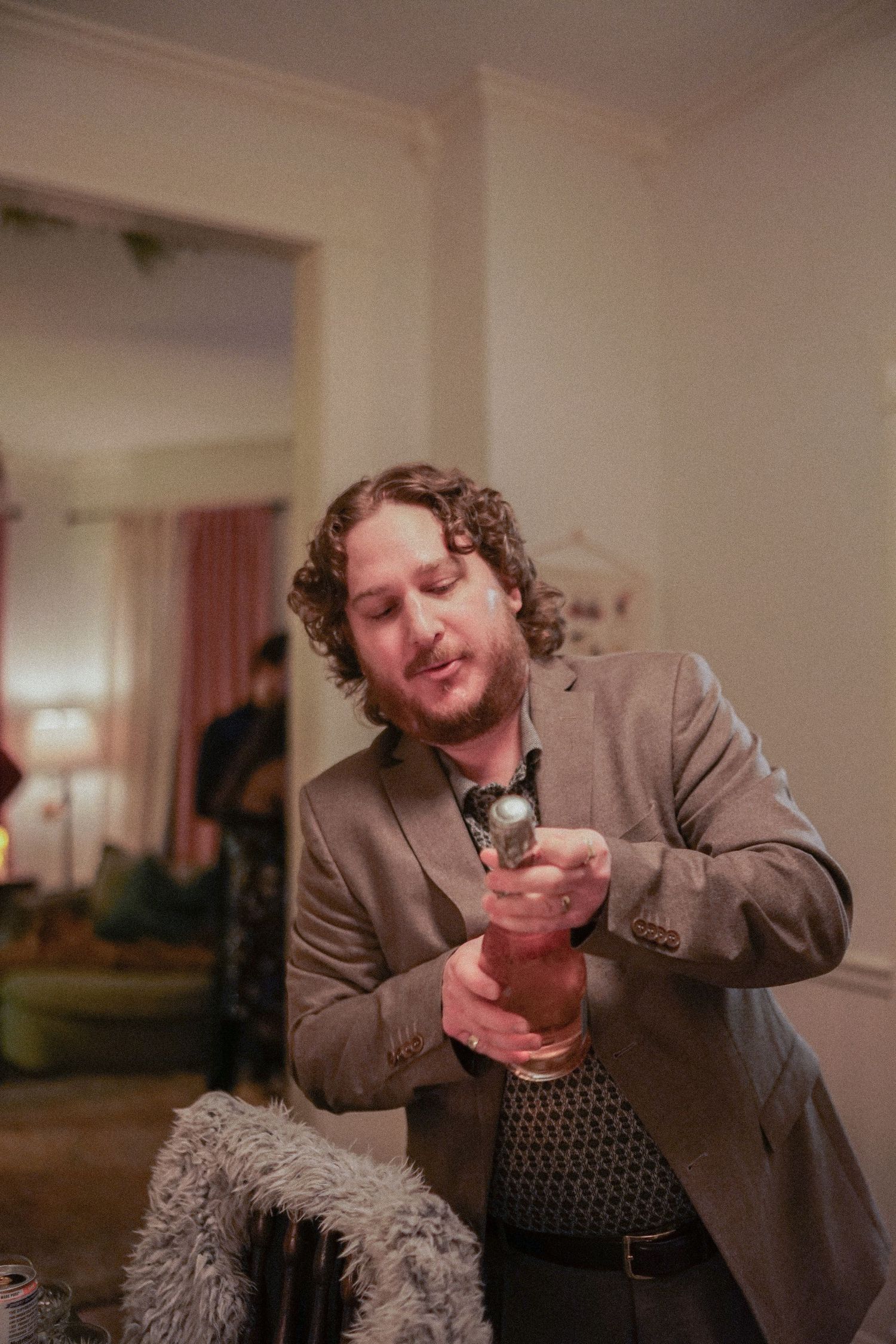 Person in brown suit jacket performing expressively in an indoor setting.