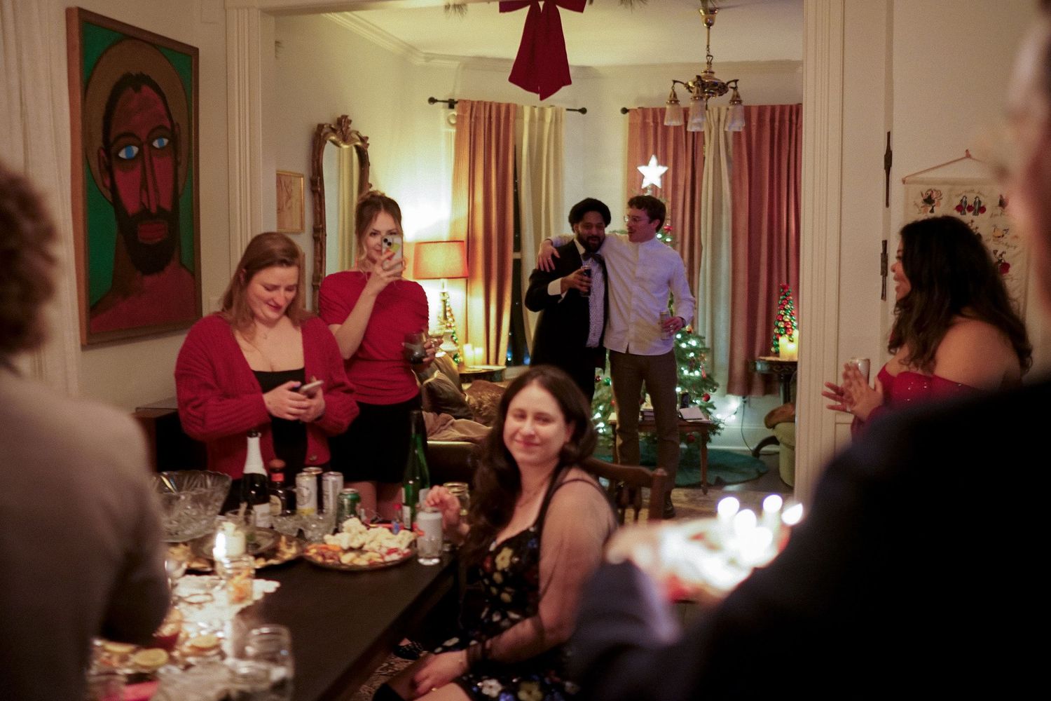 A group celebrates at a holiday party with festive decorations and string lights.