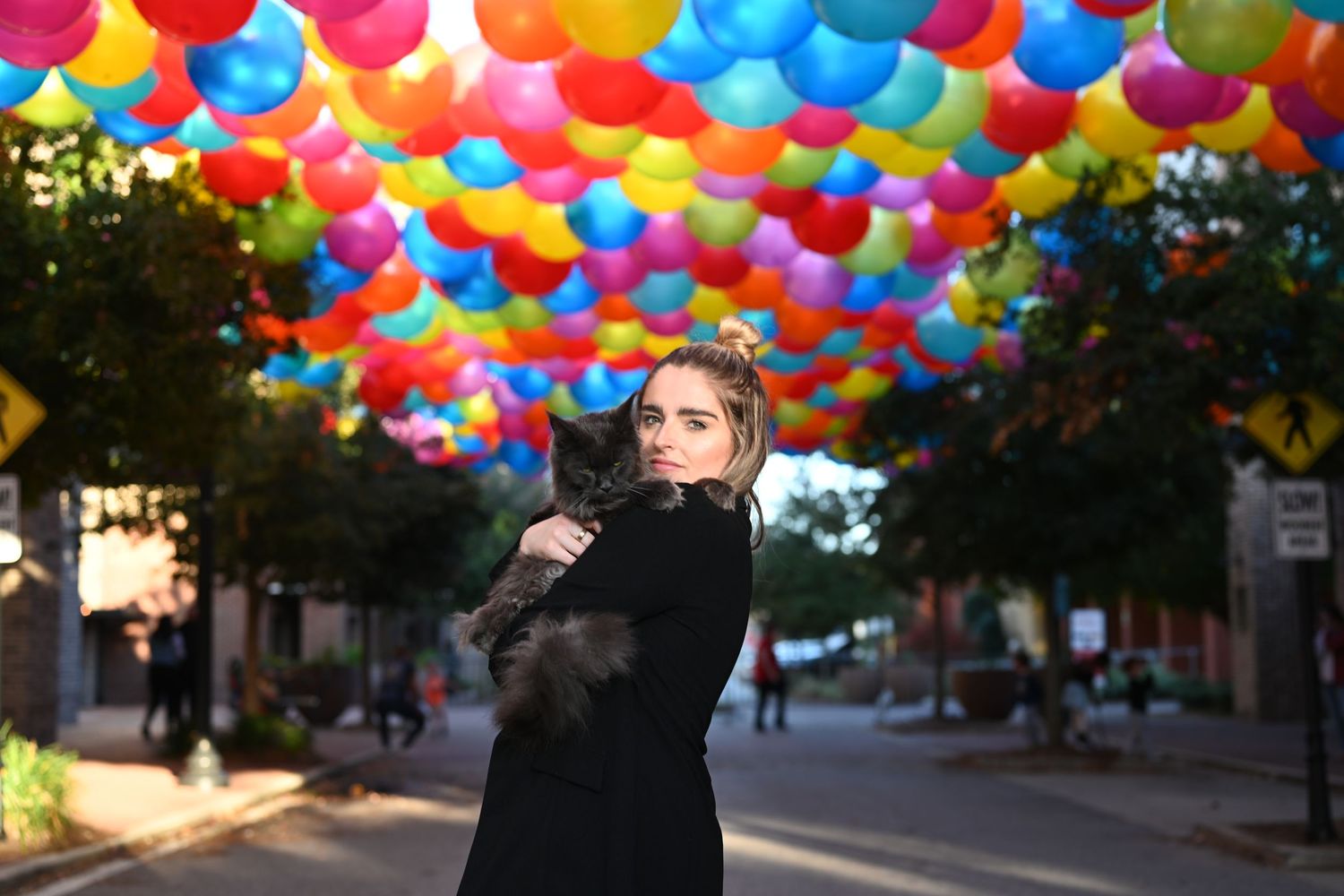 Vibrant multicolored balloons create a festive canopy over an outdoor street or walkway.