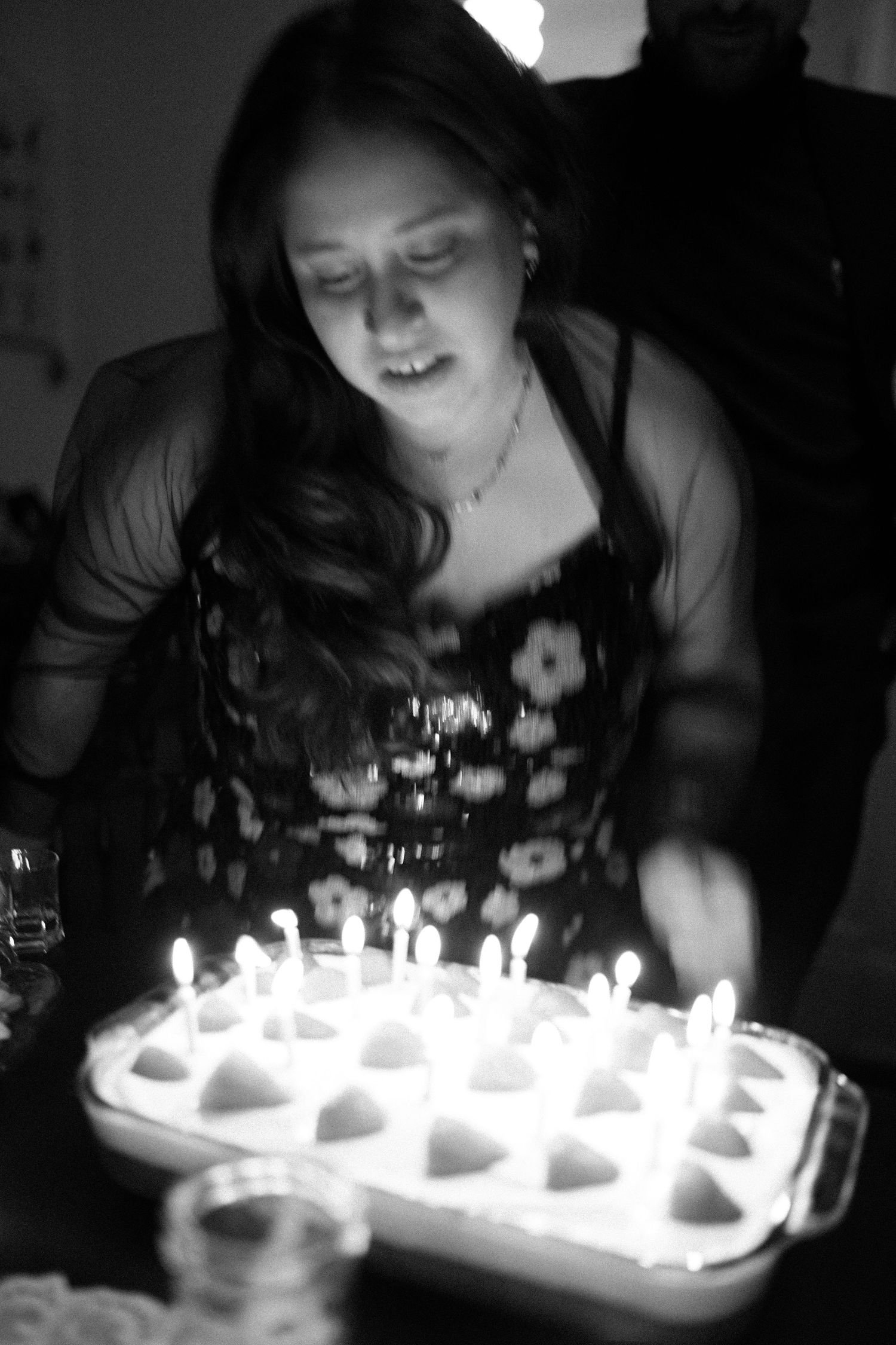 A birthday celebration with lit candles on a dessert tray in black and white.