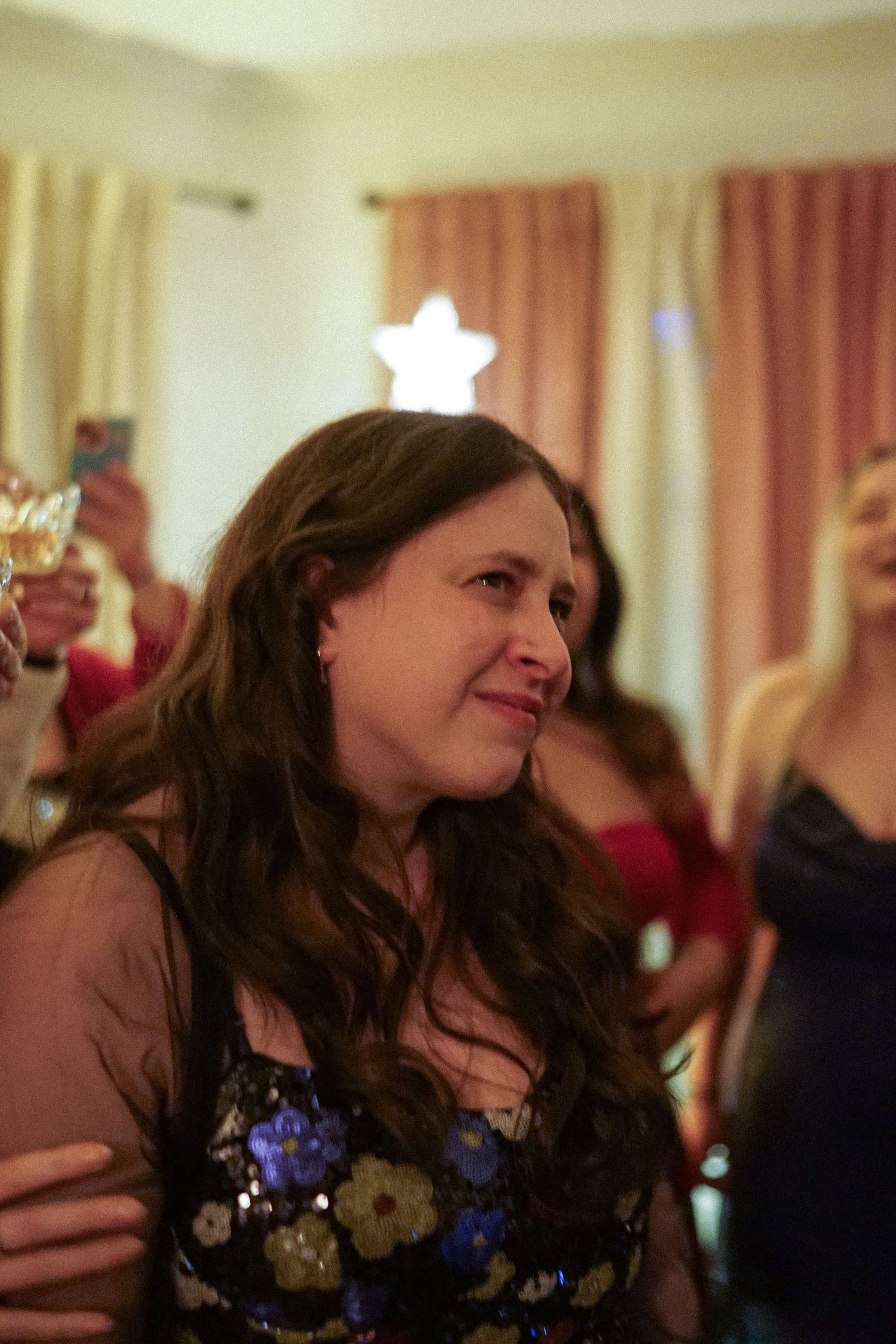 A guest in a floral dress enjoying a festive celebration with a star decoration in the background.