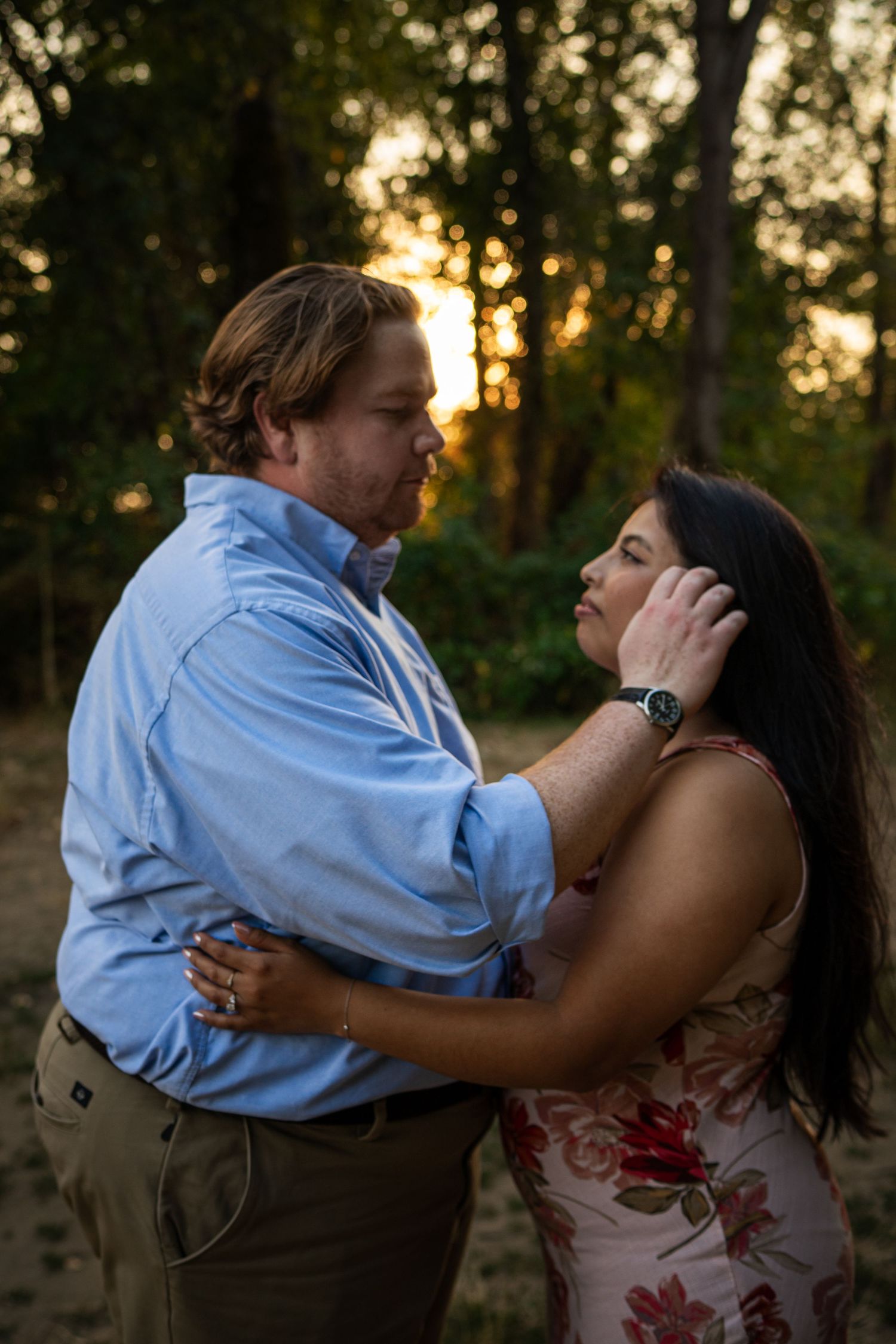 A couple sharing an intimate moment during sunset in an outdoor setting.