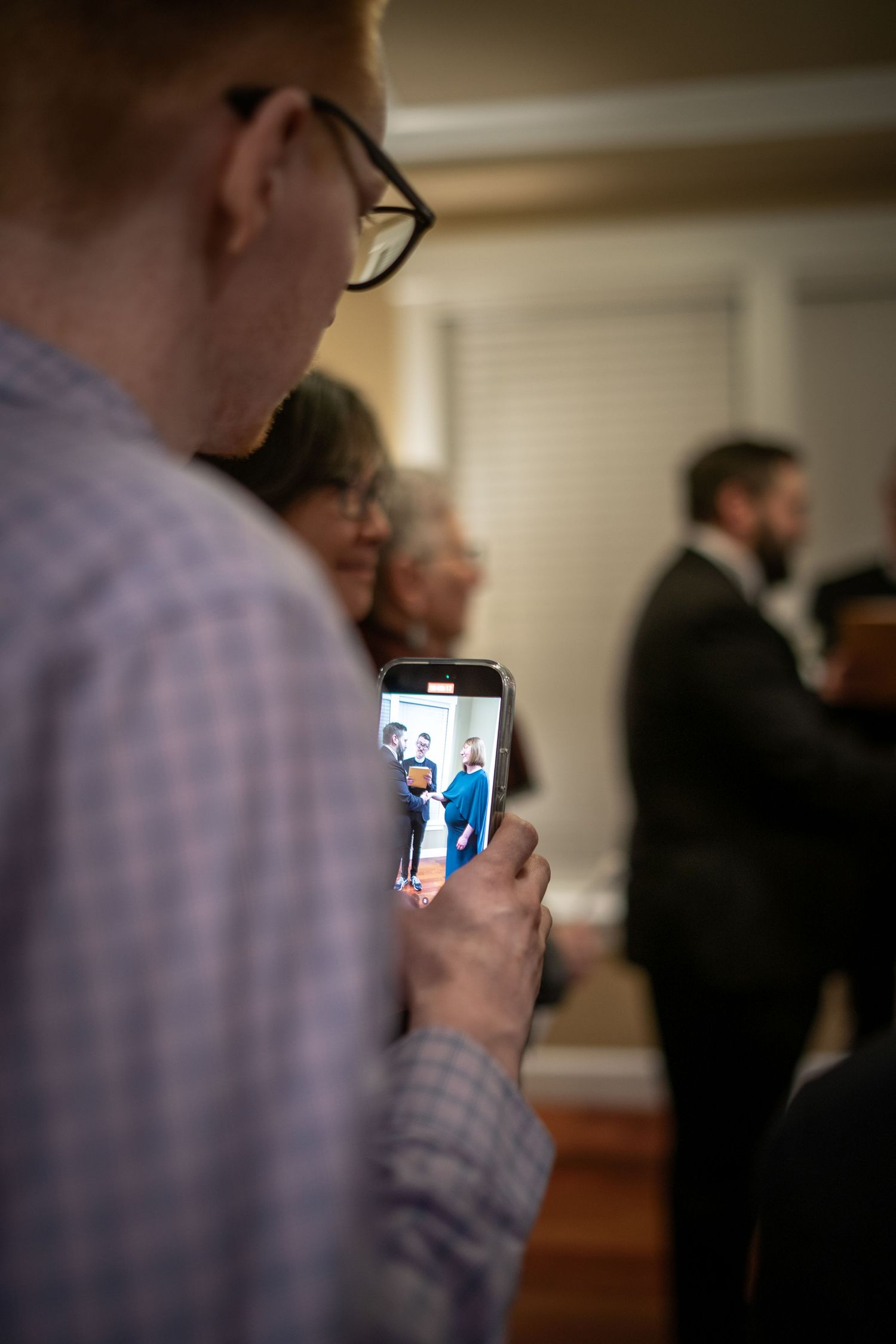 Someone holding a mobile phone displaying photos during a social gathering.