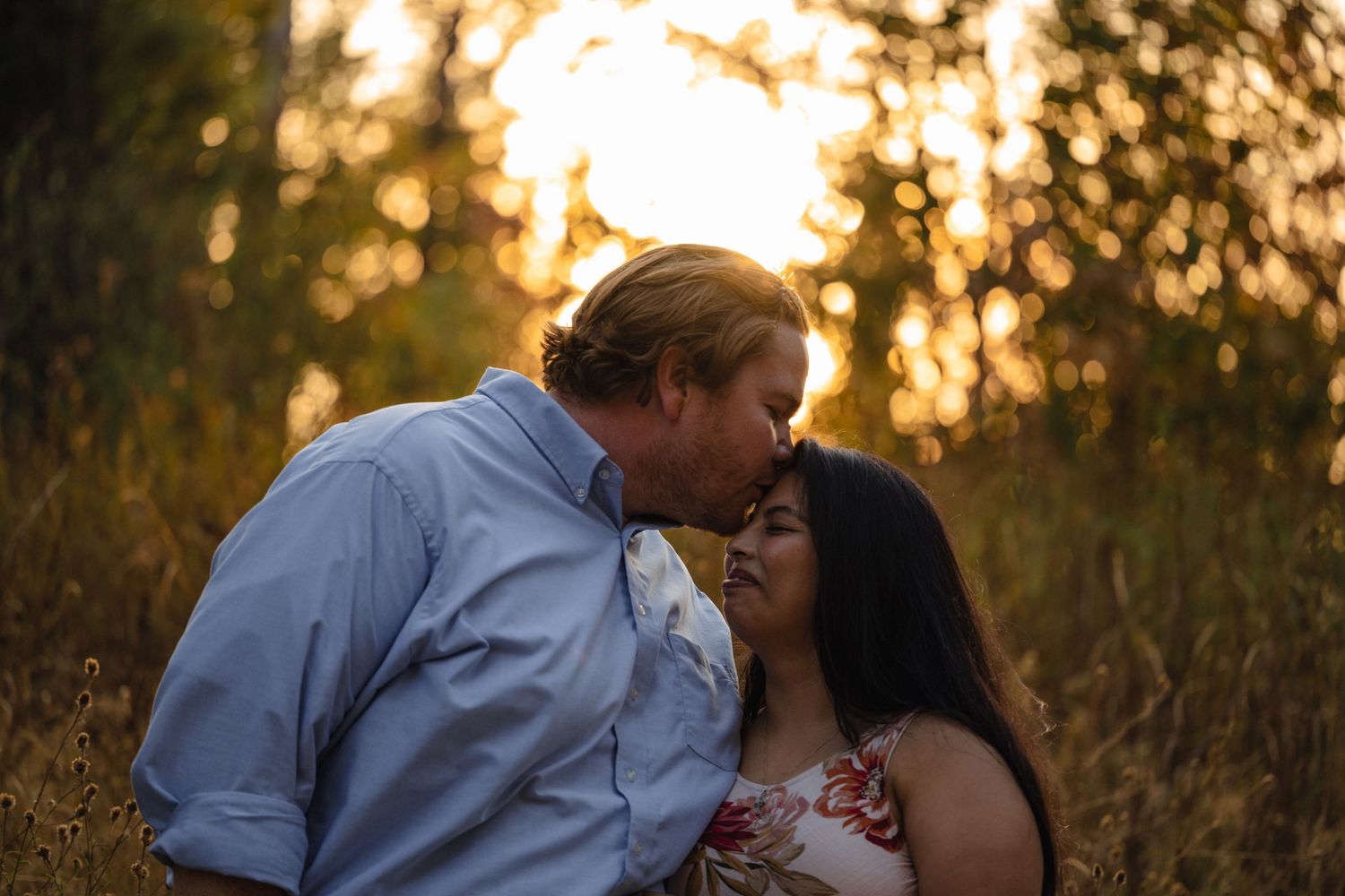 Couple embracing in a romantic sunset photoshoot among tall grass.