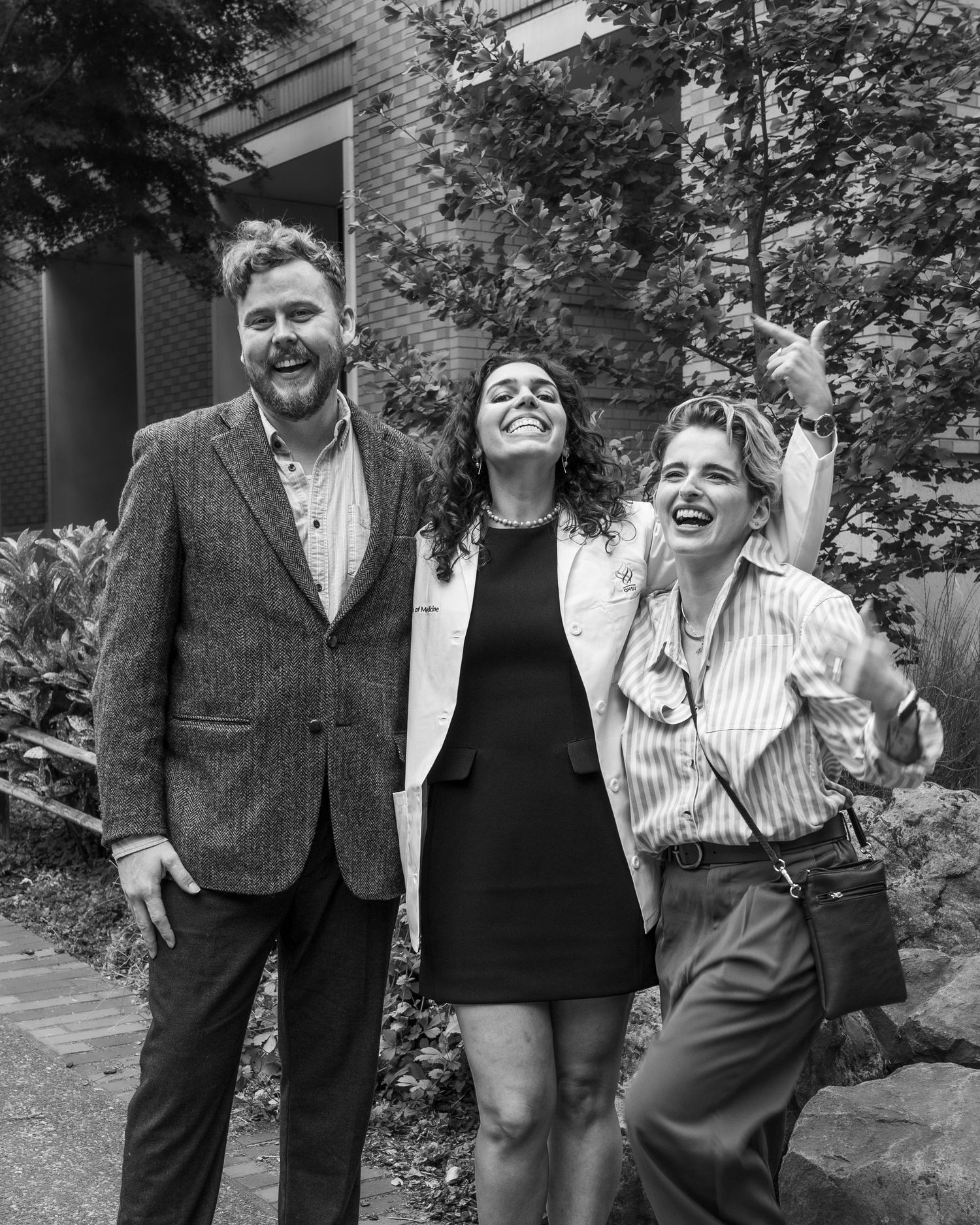 Group of people laughing and posing together outdoors in black and white photography.