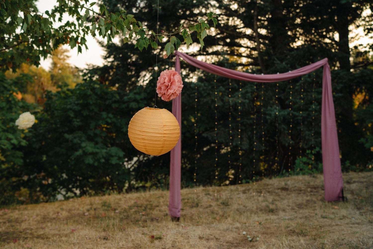 Decorative lanterns and draping fabric creating an outdoor romantic atmosphere at sunset.