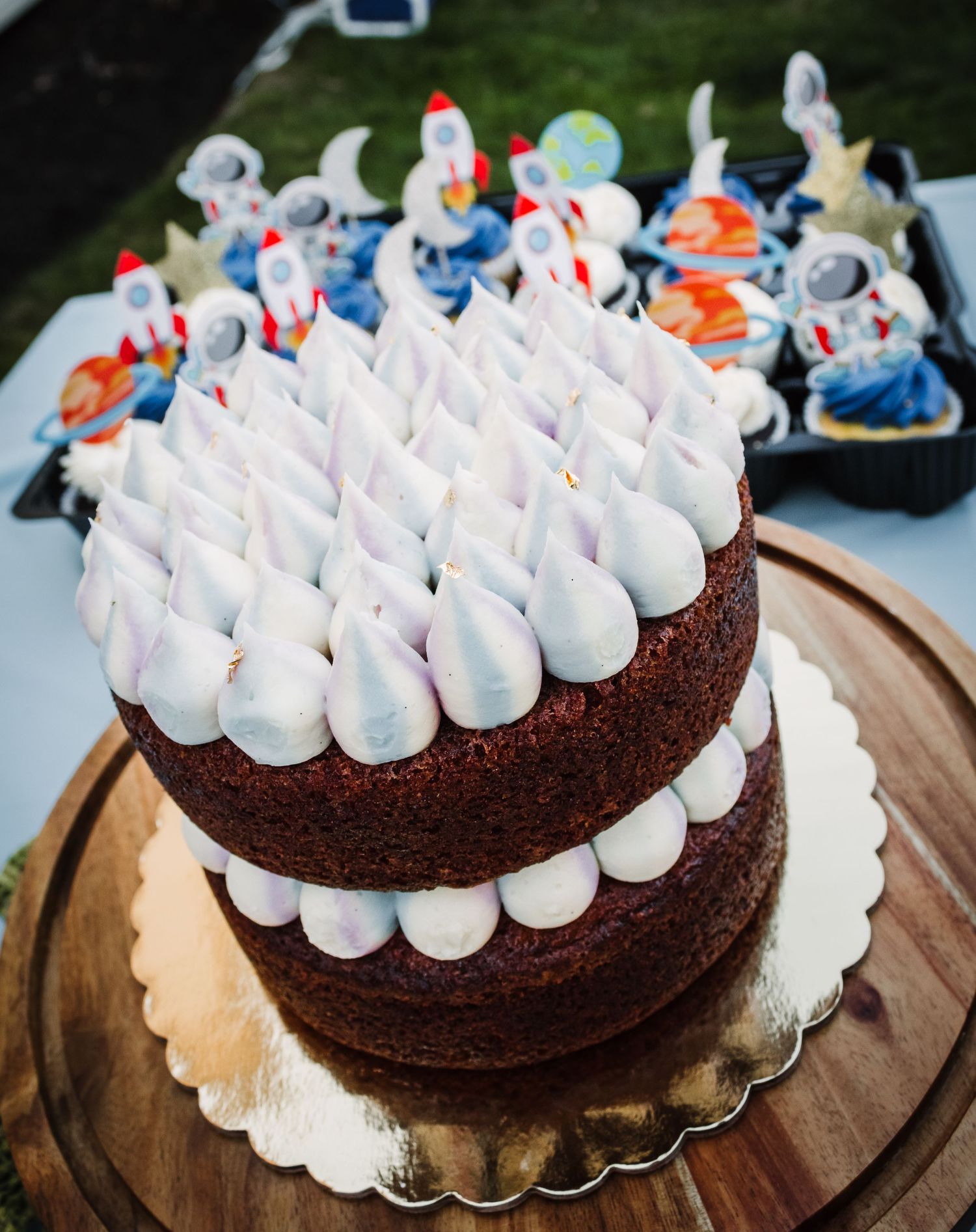 Chocolate layer cake decorated with white meringue dots on a rustic wooden serving board.