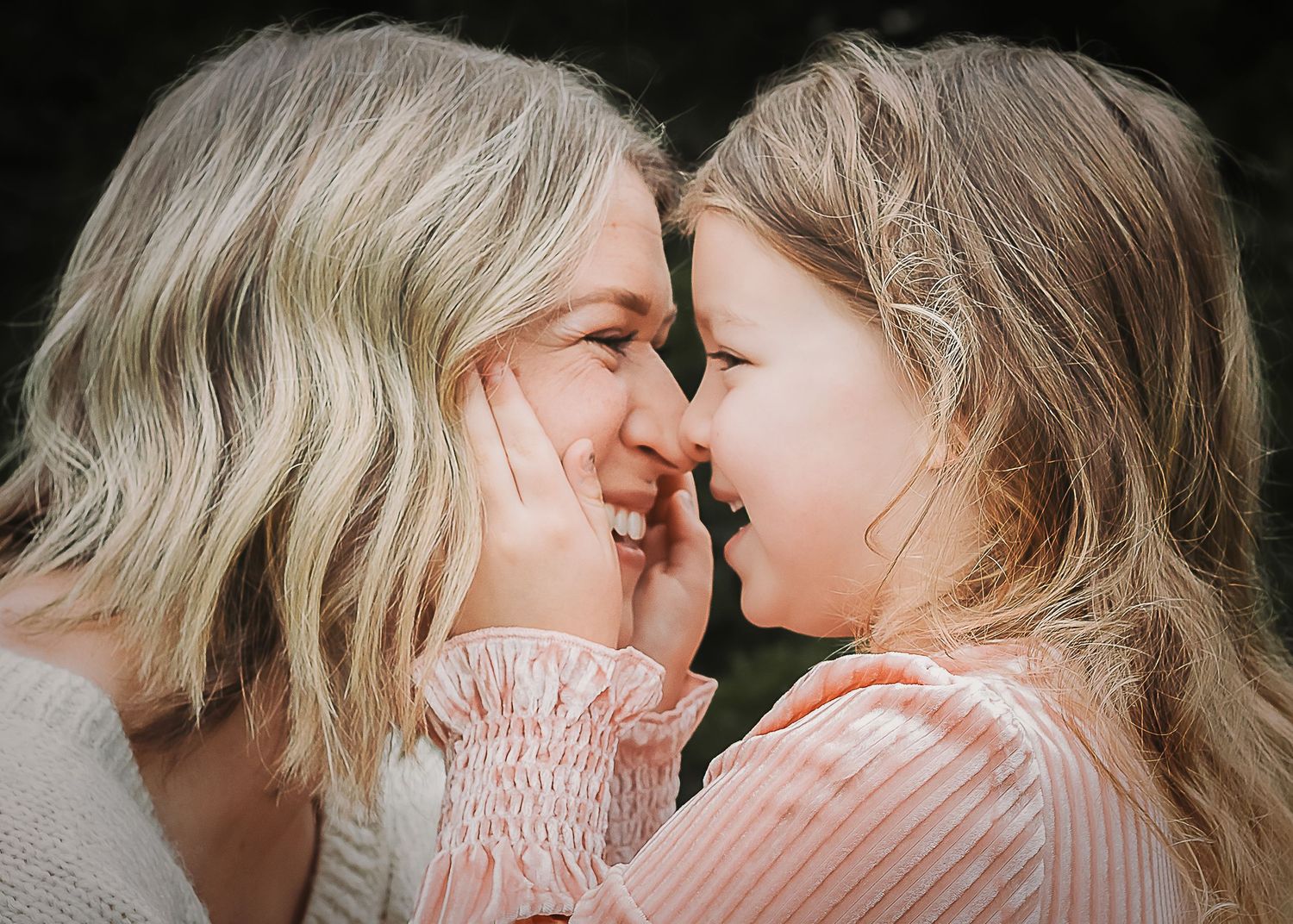 Two people in pink outfits share an intimate moment against a light background.