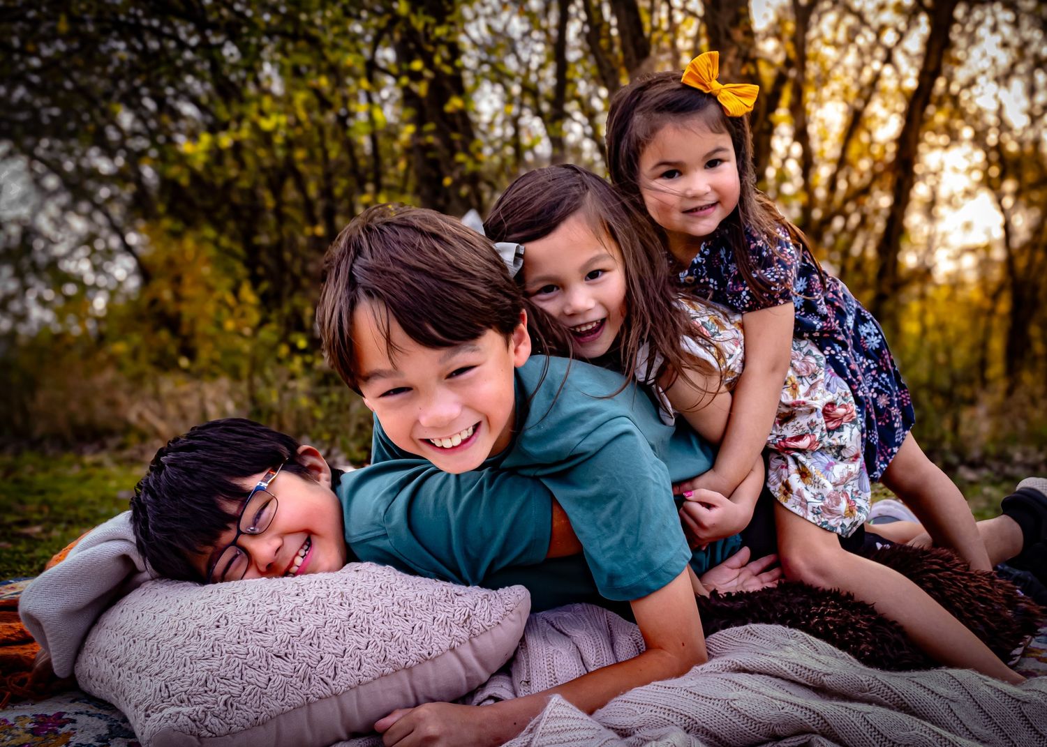 People lying down together on a blanket during sunset, sharing a playful moment.