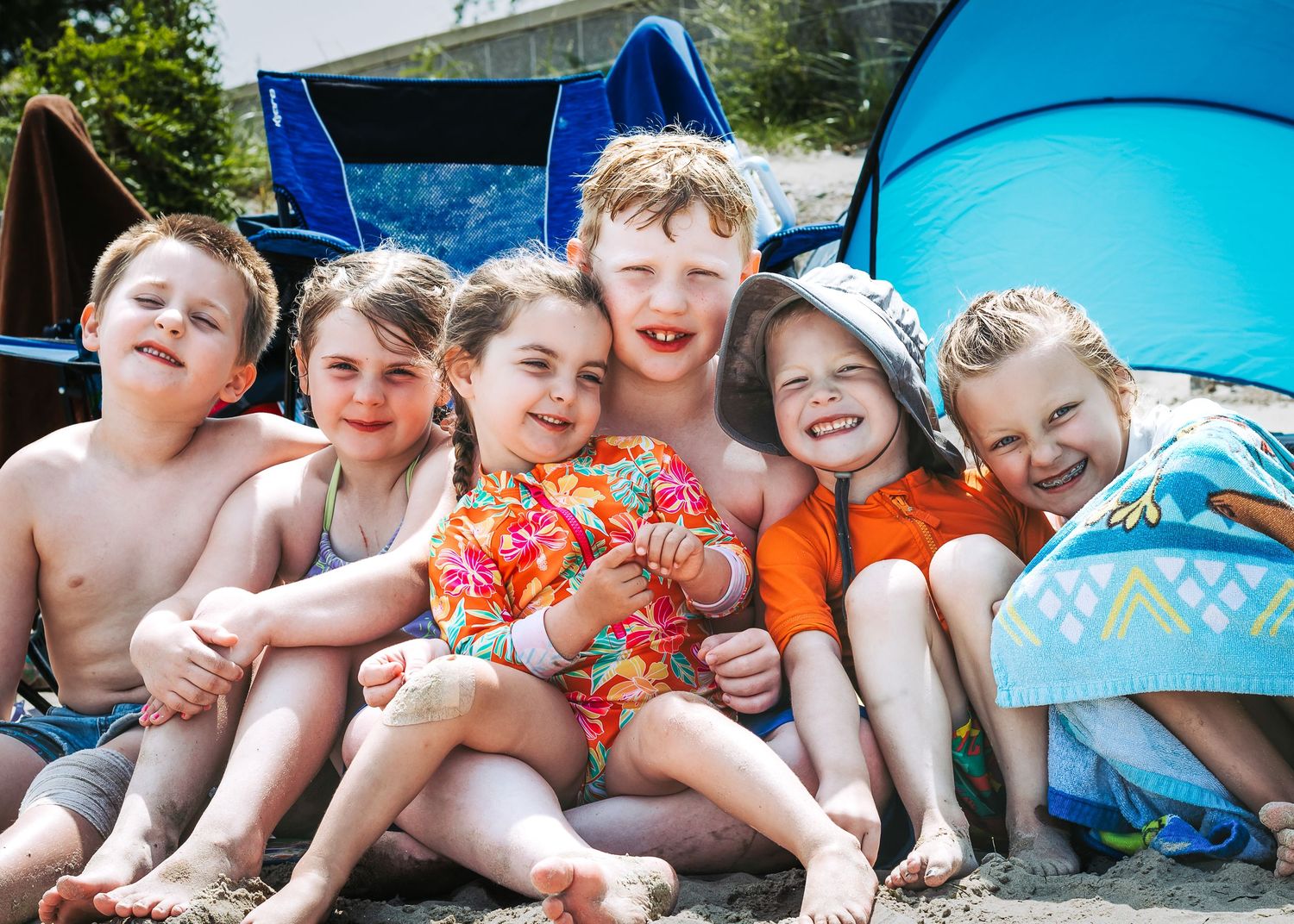 Children lying side by side on blue cushions outdoors during summer.