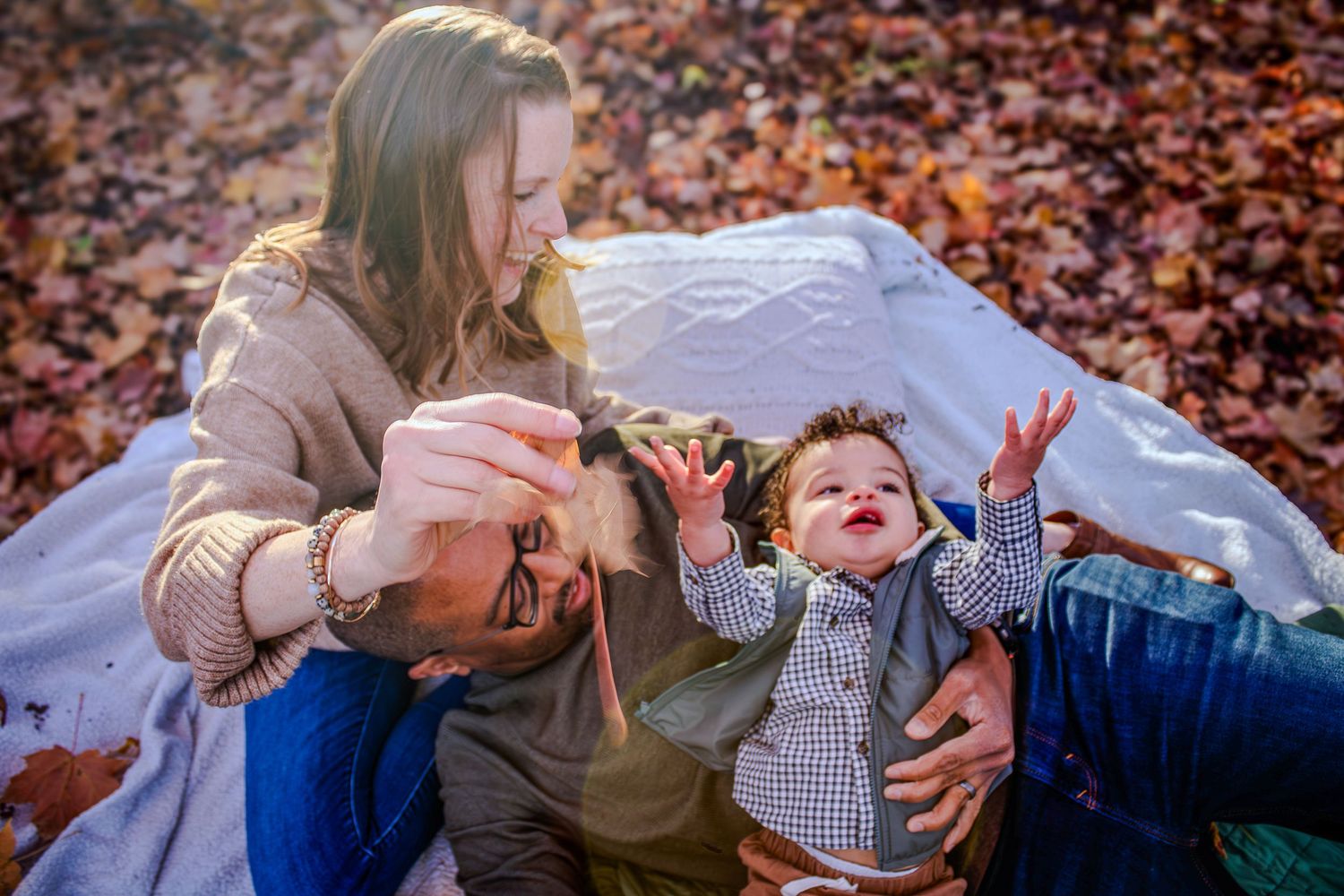 Couple laying in colorful autumn leaves sharing intimate moments against fall foliage background.