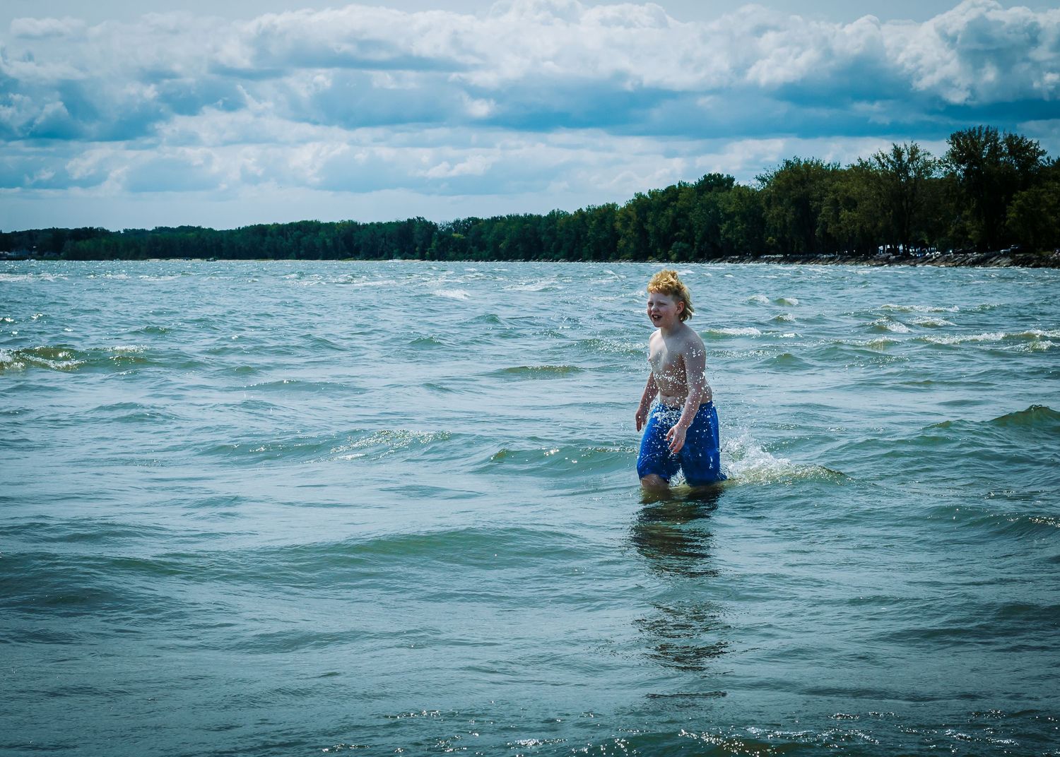 A sequence of ocean shoreline photos shows people wading in choppy blue-green waters on a cloudy summer day.