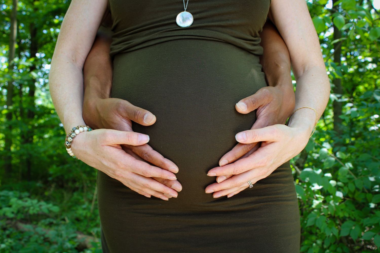 Series of photos showing hands cradling a pregnant belly in an outdoor wooded setting.