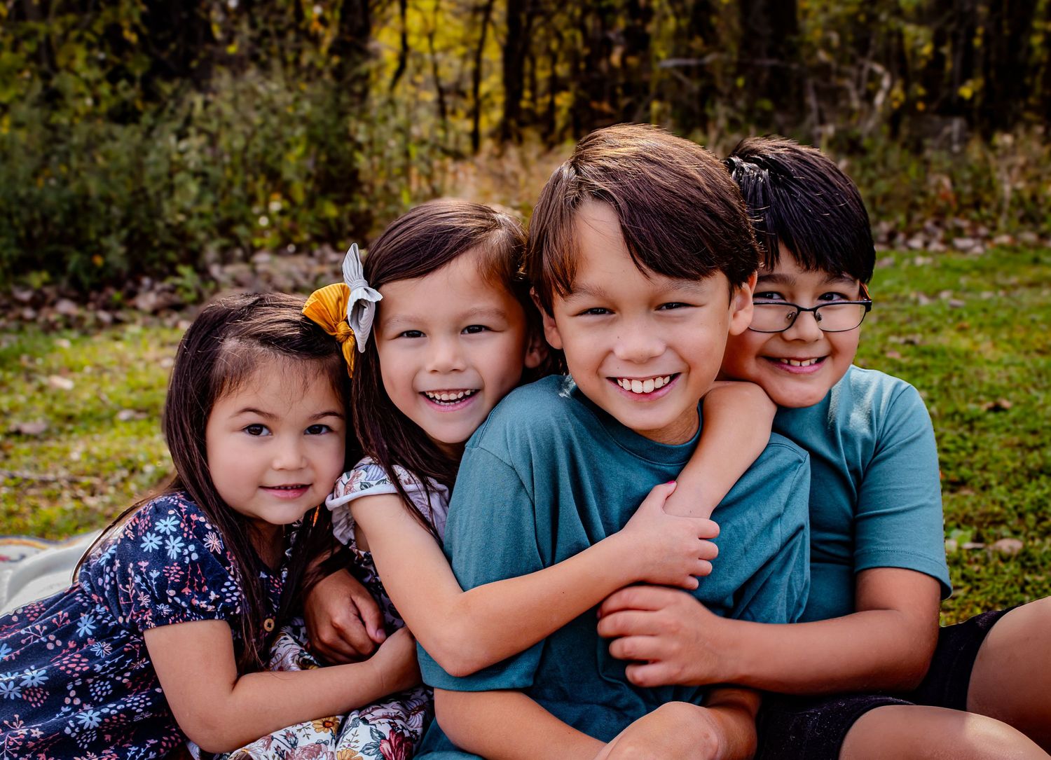 Four candid photos show playful outdoor moments during a sibling photoshoot in nature.