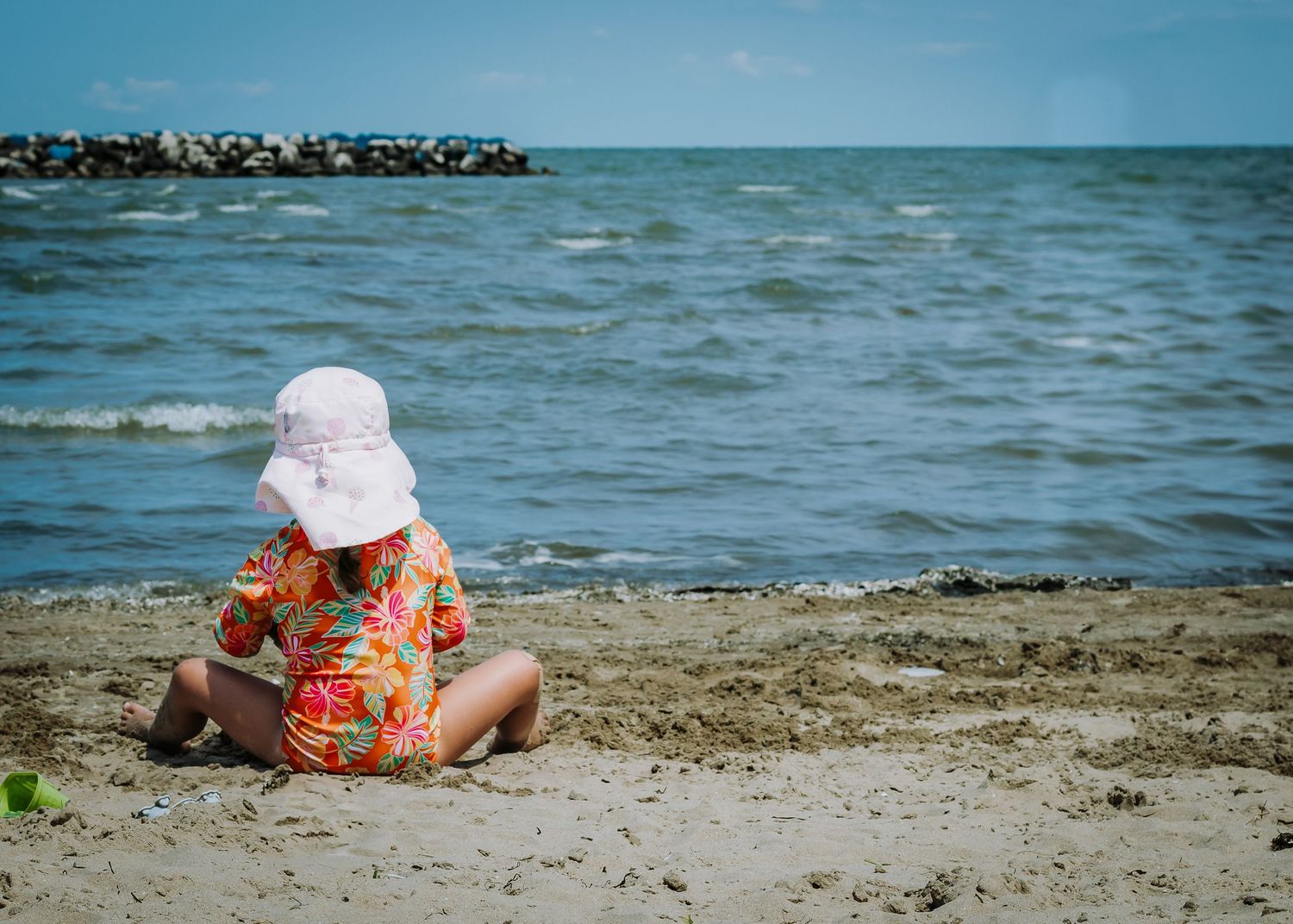 Beach scene with someone relaxing on sandy shoreline near blue ocean waters.