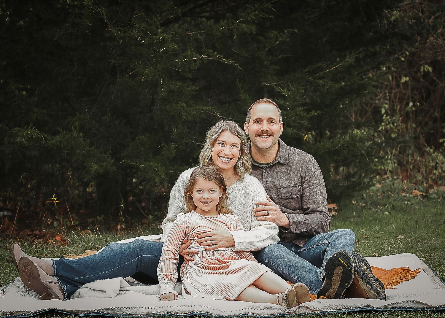 A sequence of outdoor family portraits showing tender moments between parents and child on blankets in nature.