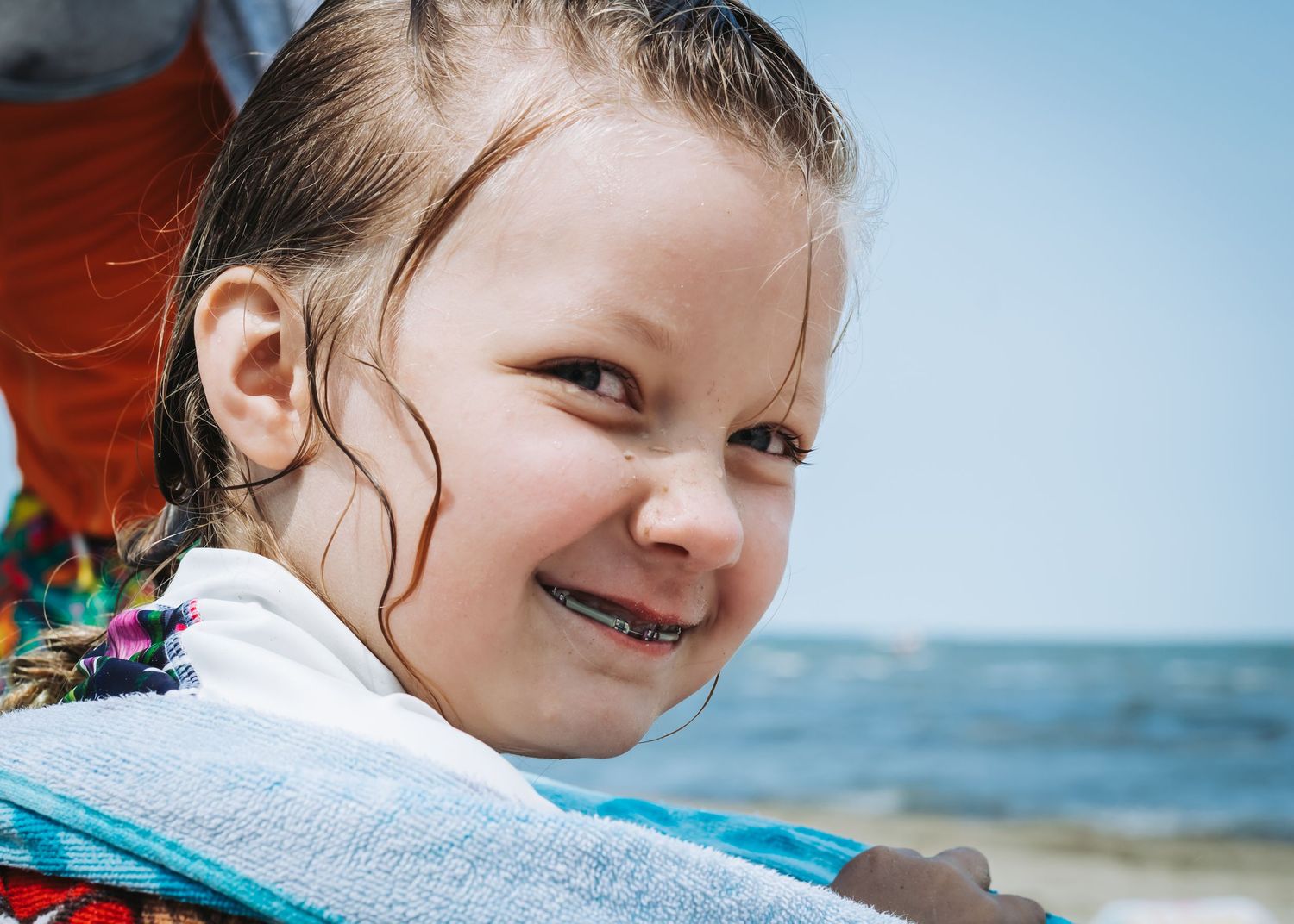 Close up portrait against blue ocean background on sunny beach day.