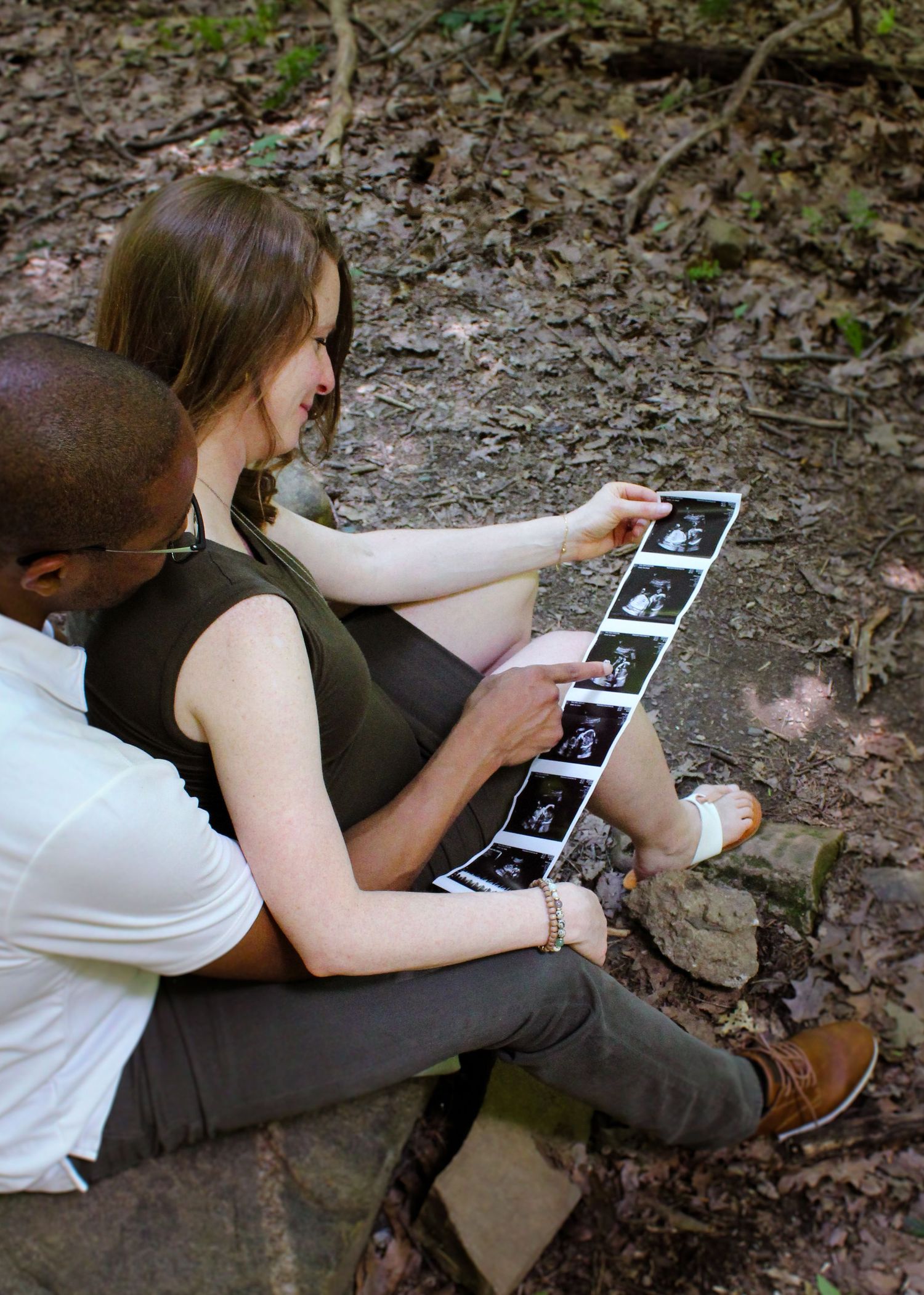 A series of images showing people examining and looking at ultrasound photos while sitting on a forest ground.