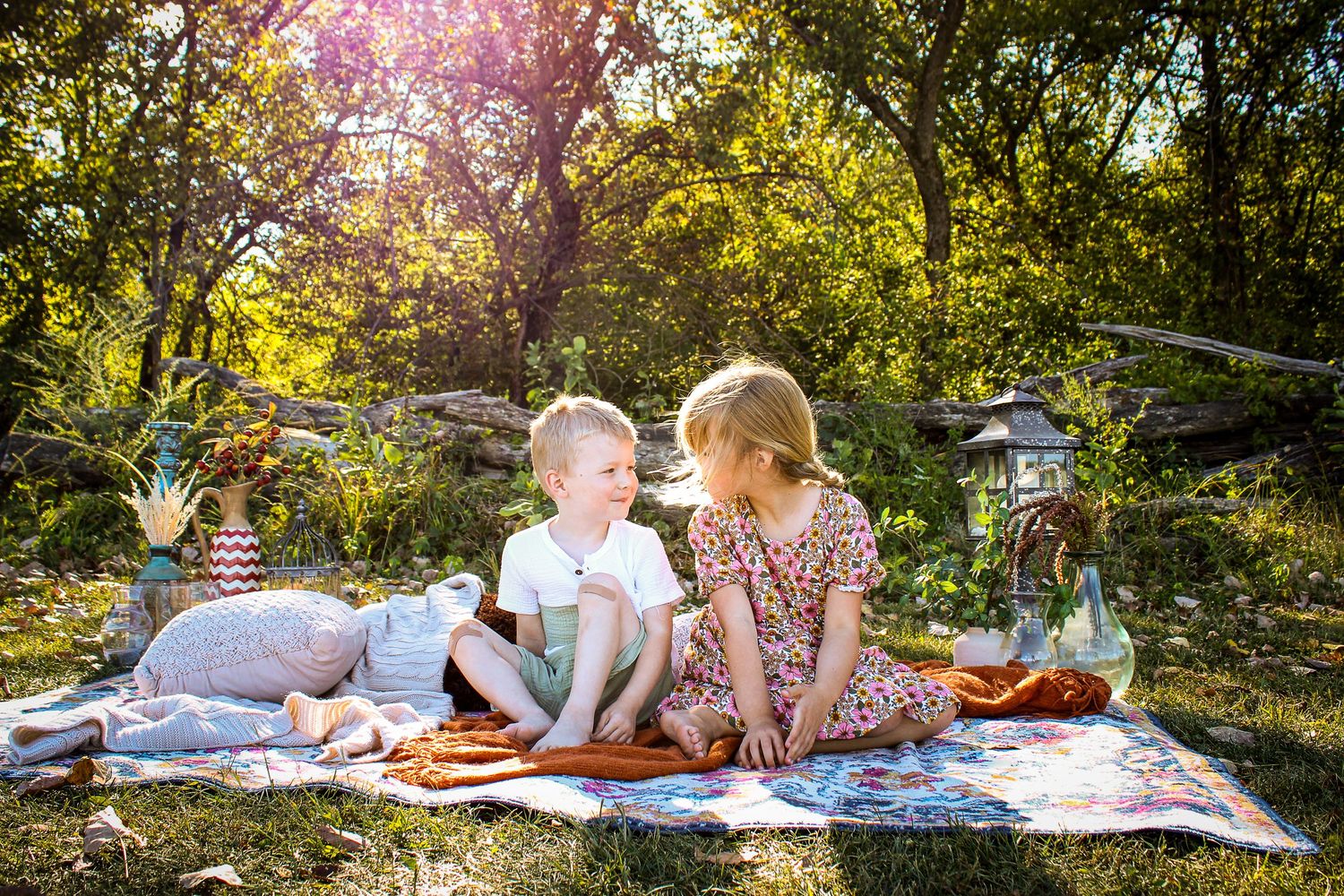 Family enjoying picnic on blanket under trees during golden sunset.