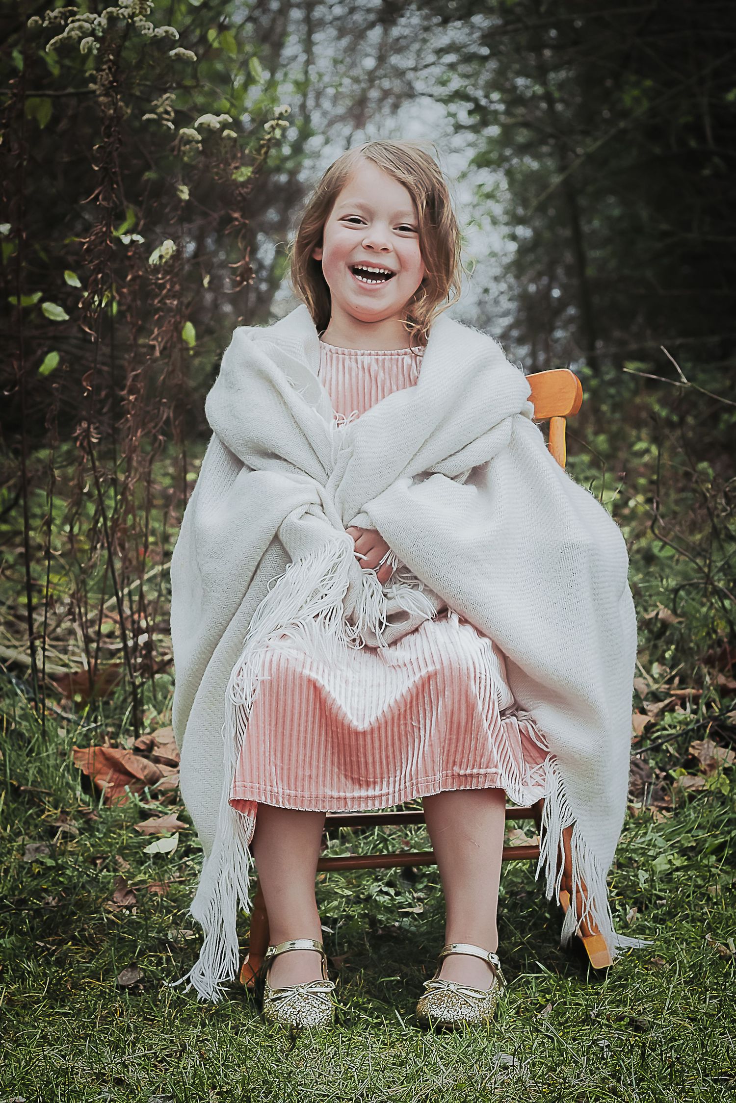Person in white shawl sitting outdoors surrounded by natural greenery.