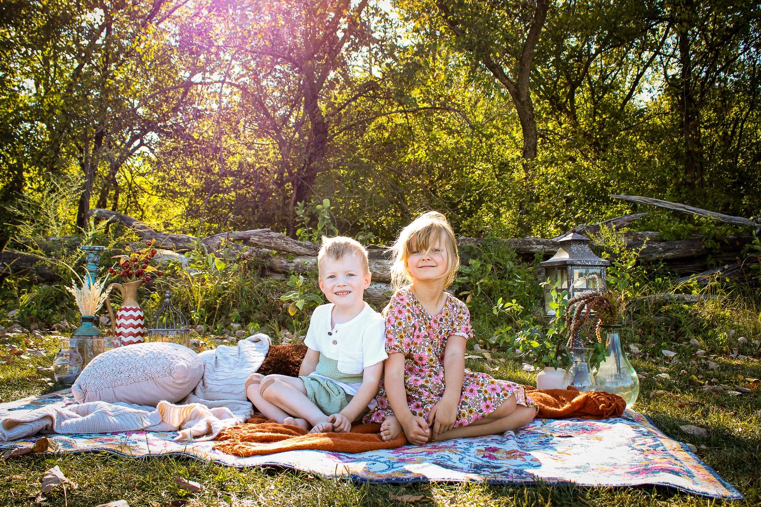 Family relaxing on blanket in park during golden hour sunset.