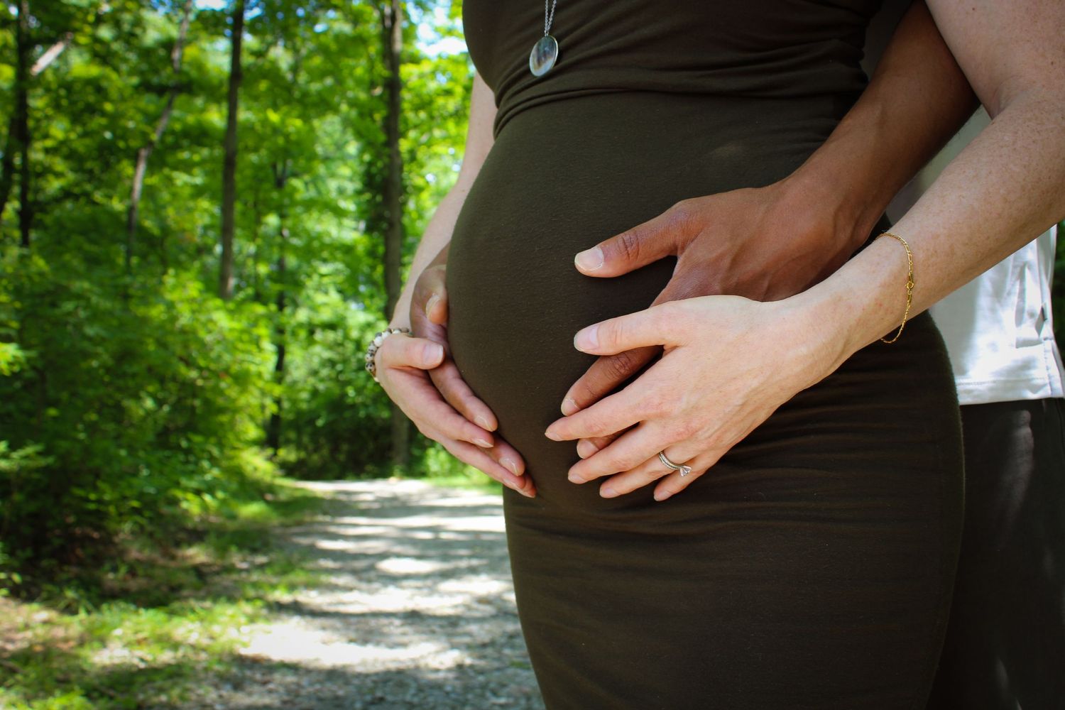 A pregnancy progression photo collage showing a growing baby bump against a wooded forest background.