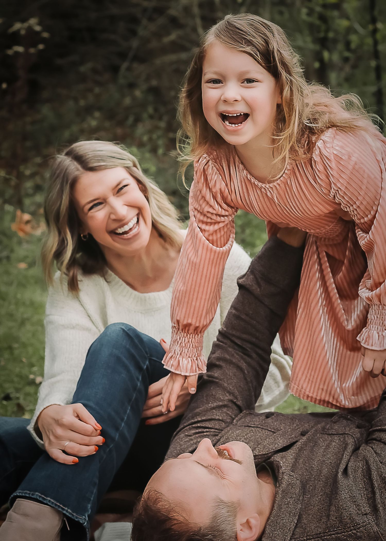 A family shares joyful laughter while enjoying candid moments together in a lush outdoor setting wearing coordinating outfits.