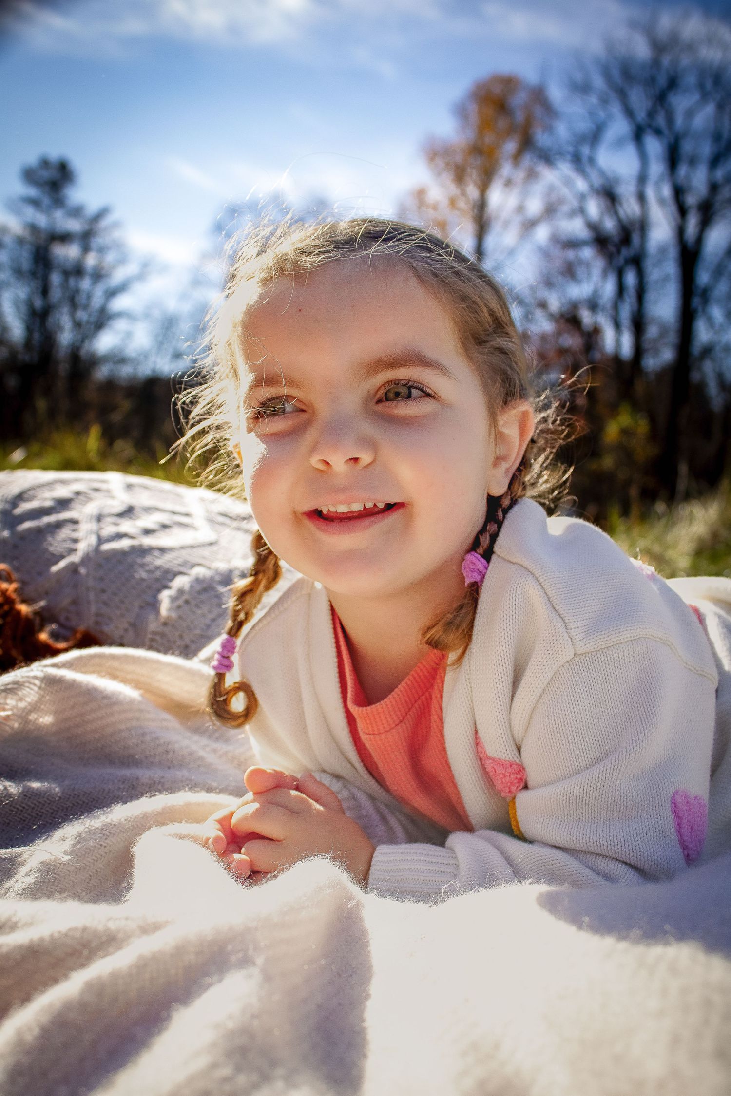 A series of similar photos show someone lying in the bright snow with a white sweater on a sunny winter day.