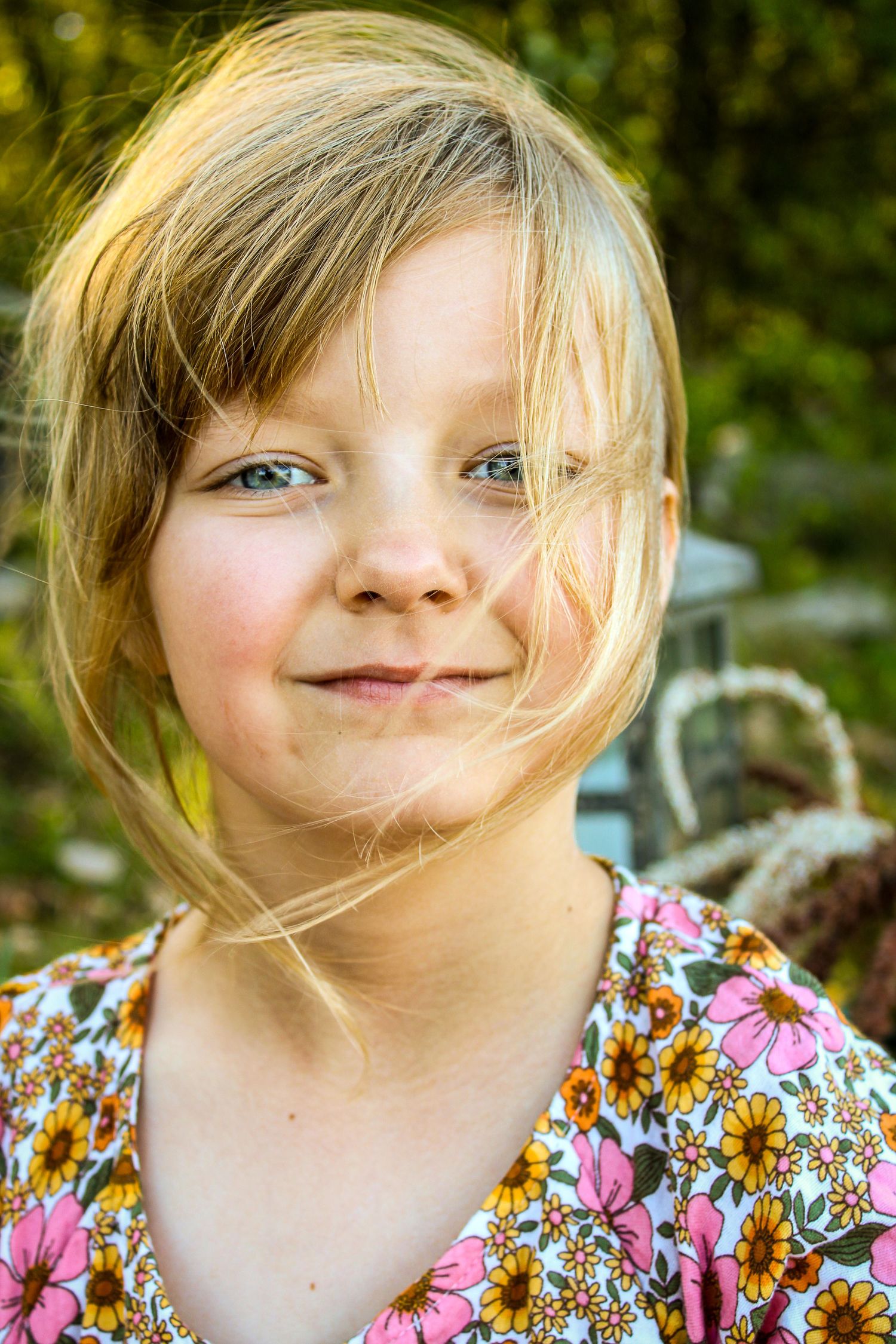 Three close-up shots captured outdoors showing a floral print dress against a natural green background.