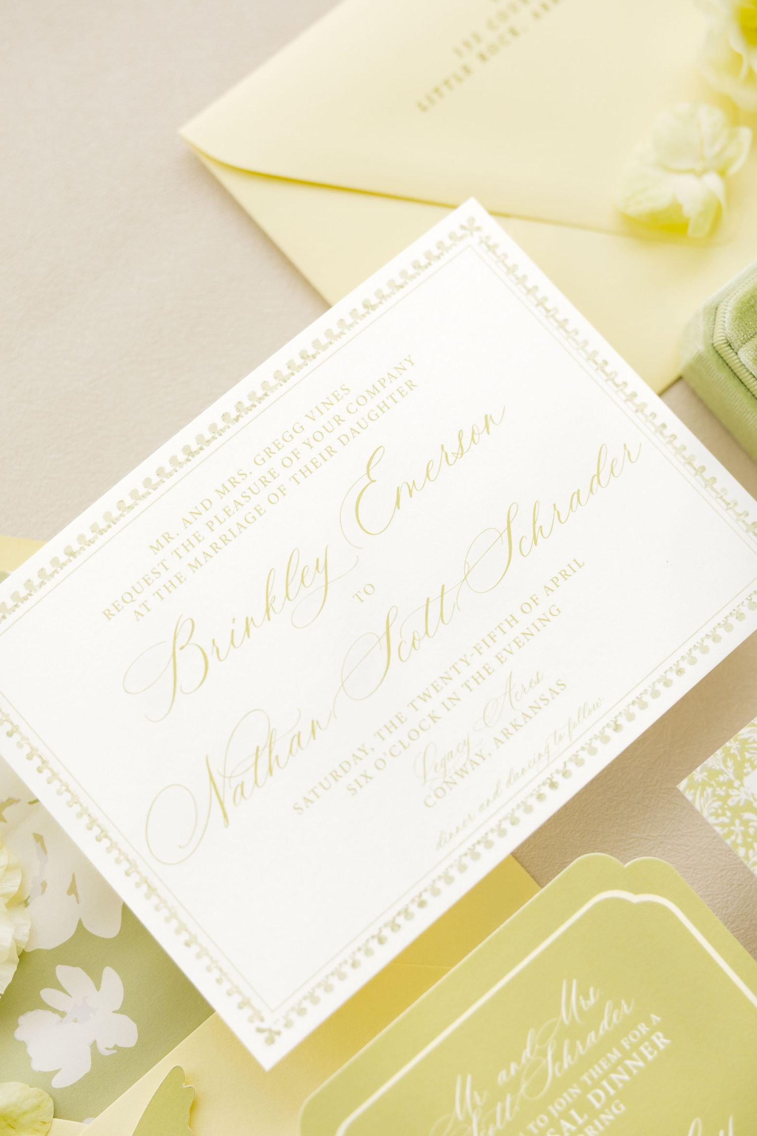 Elegant yellow and white wedding invitation suite with gold calligraphy script on a soft neutral background.