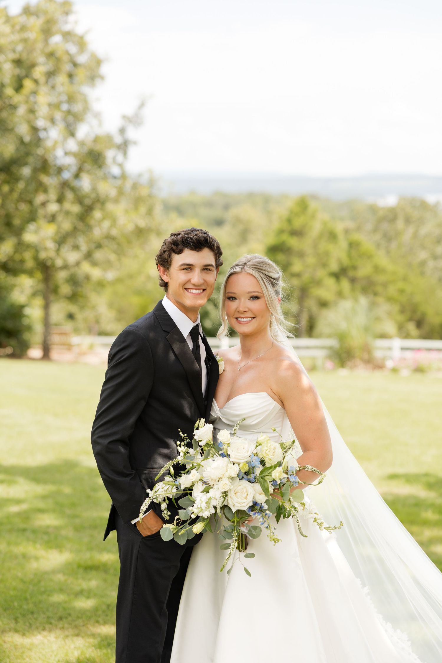 Wedding couple poses with white floral bouquet in sunny outdoor setting.Cabin Creek Lookout.