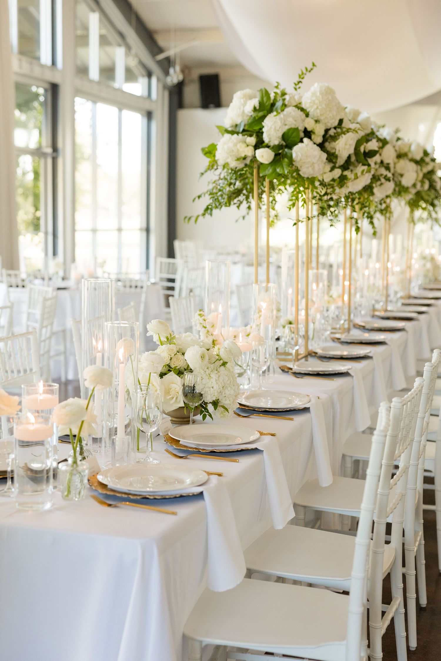 Elegant wedding reception tables set with white linens, floral centerpieces and glowing candles at Cold Springs Events.