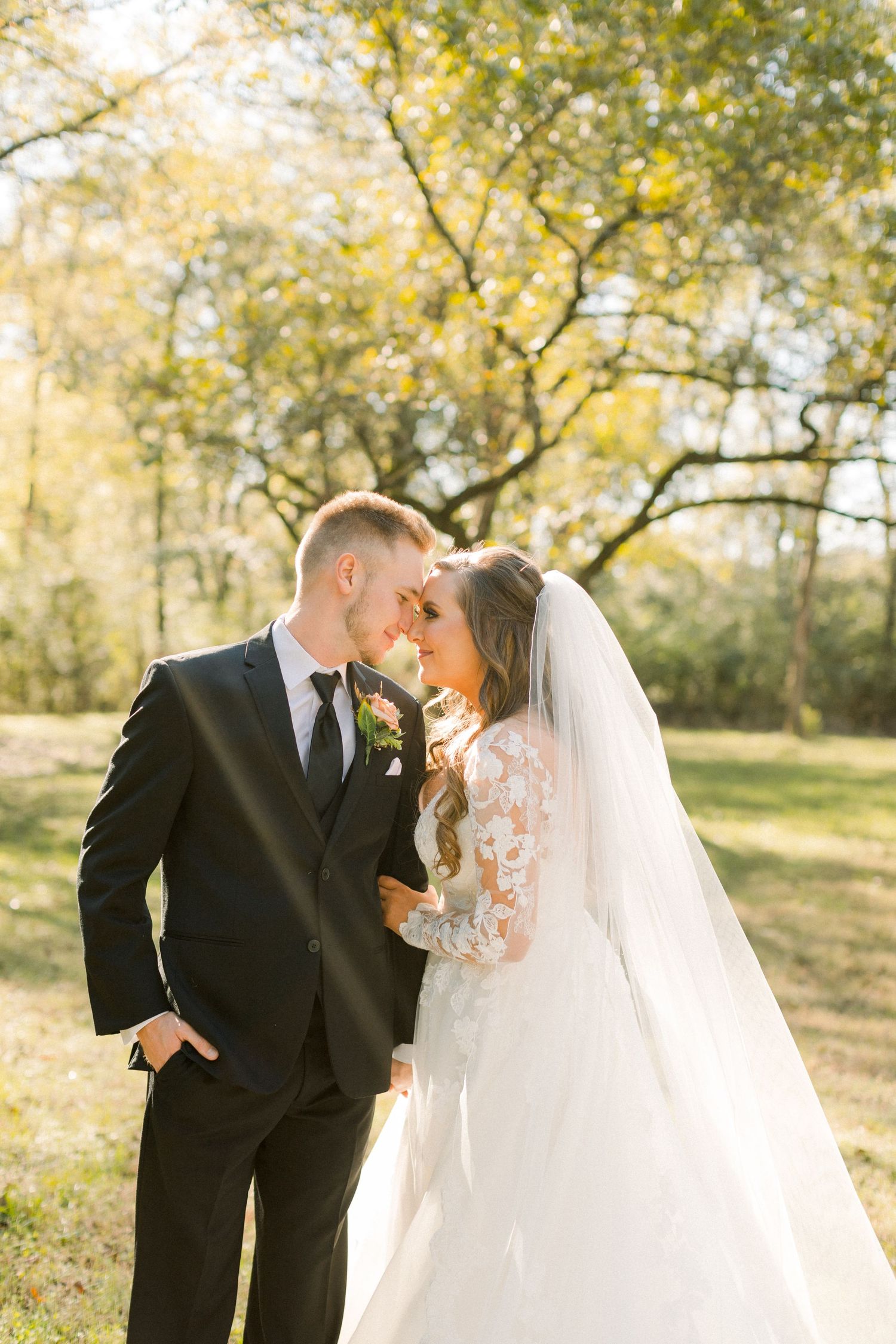 Golden sunlight filters through trees during outdoor wedding portraits.