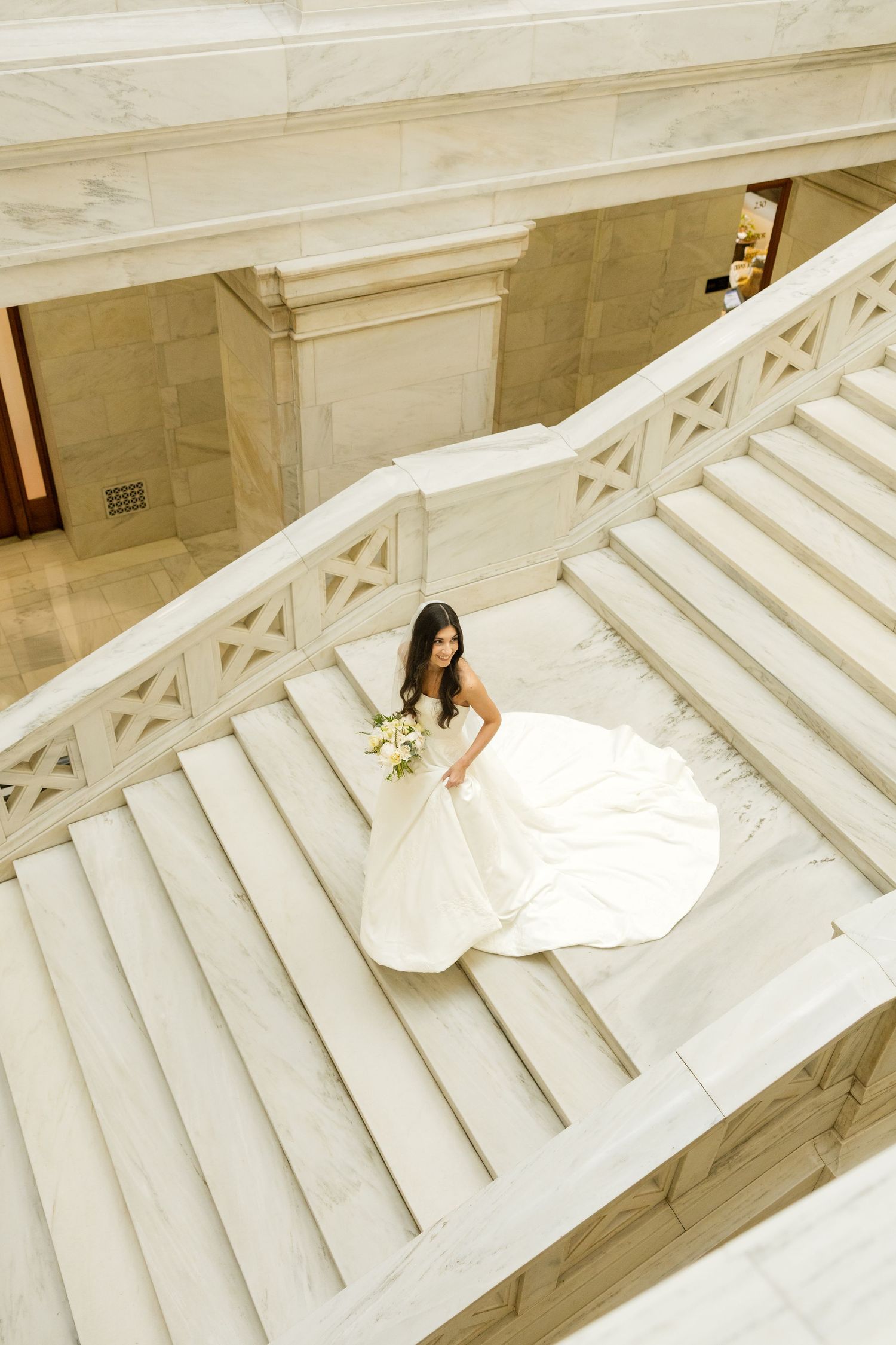 Artistic bridal portraits taken from above on dramatic white marble staircase.
