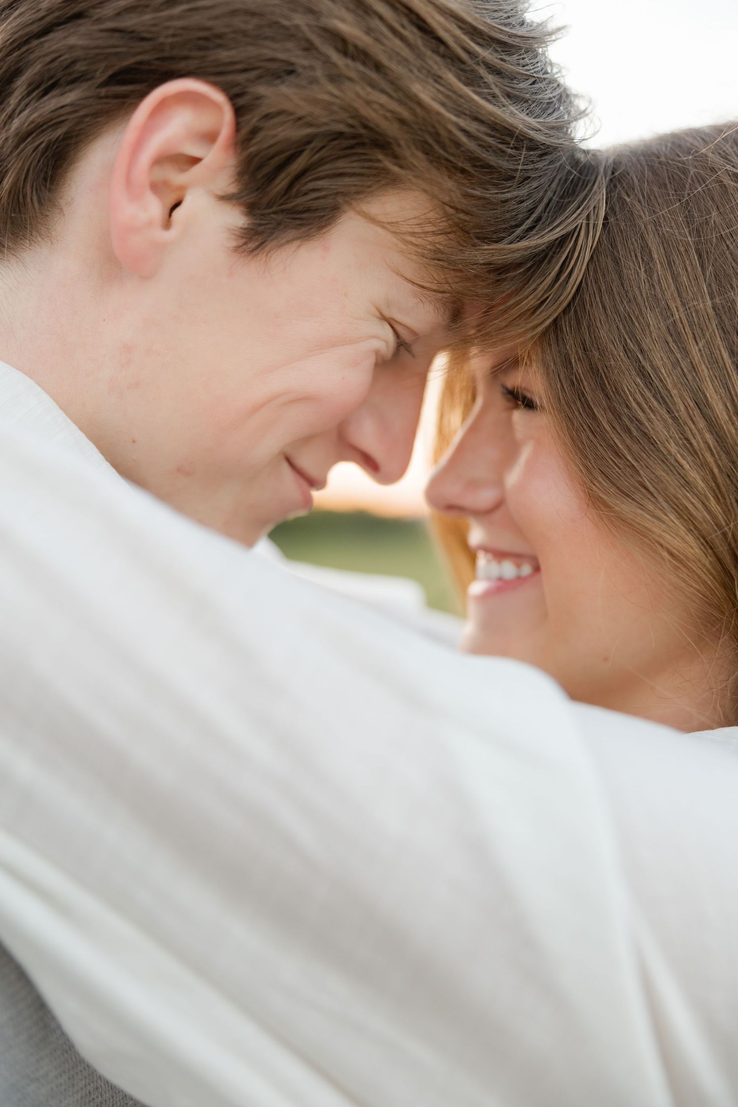 A tender moment between a couple in white clothing as they embrace and smile at each other.