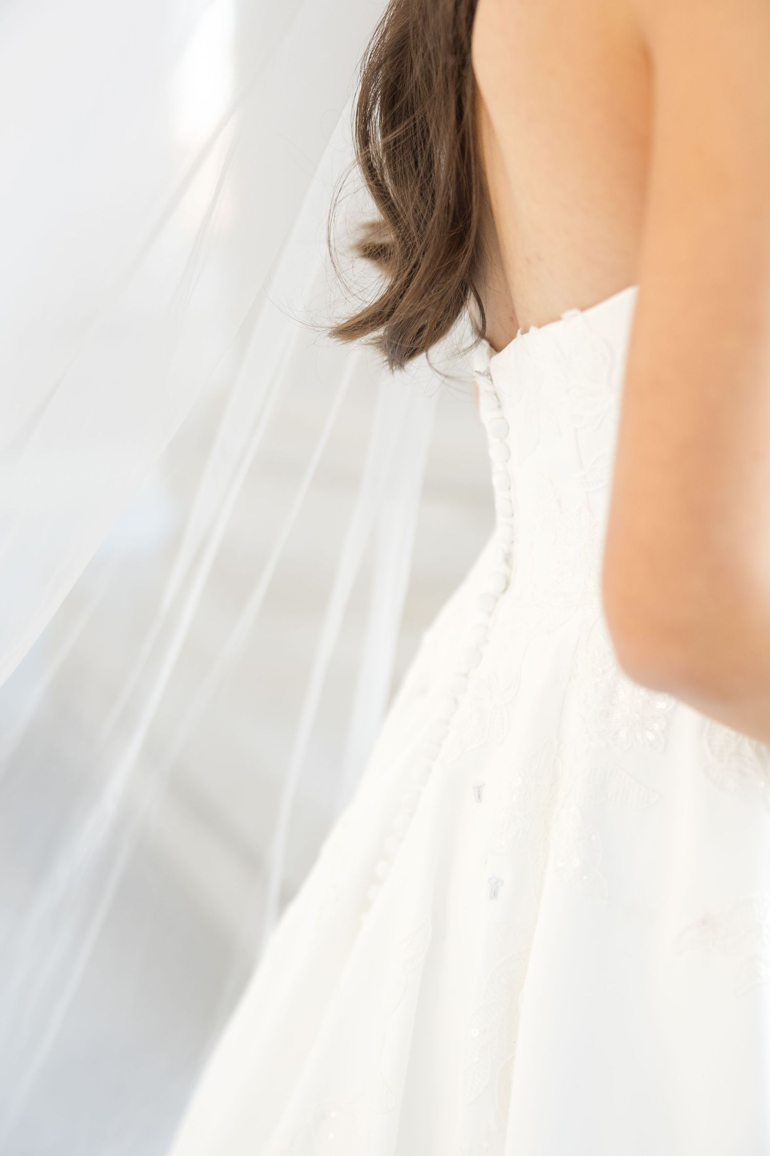 Close-up details of a white wedding dress showing delicate fabric and elegant draping.