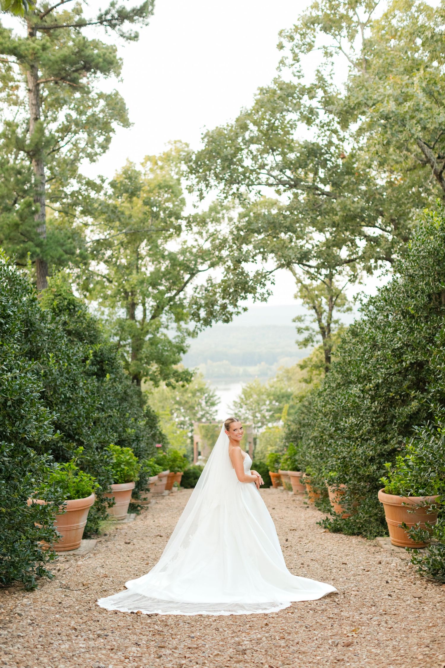 A bridal portrait in an elegant garden setting with terracotta pots and natural greenery.
