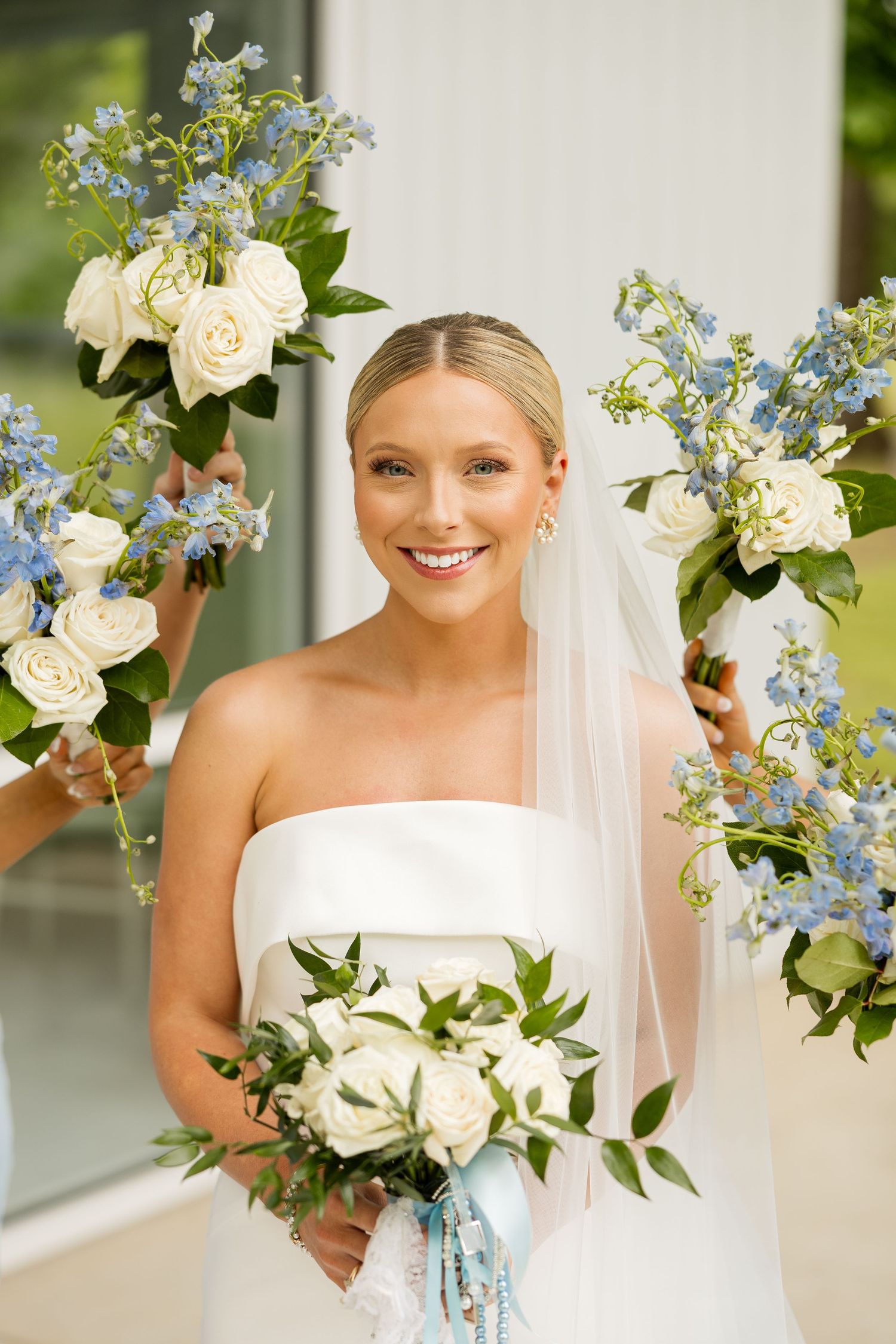 Wedding bouquet featuring white roses and light blue delphinium flowers against a white background.Cold Springs Events