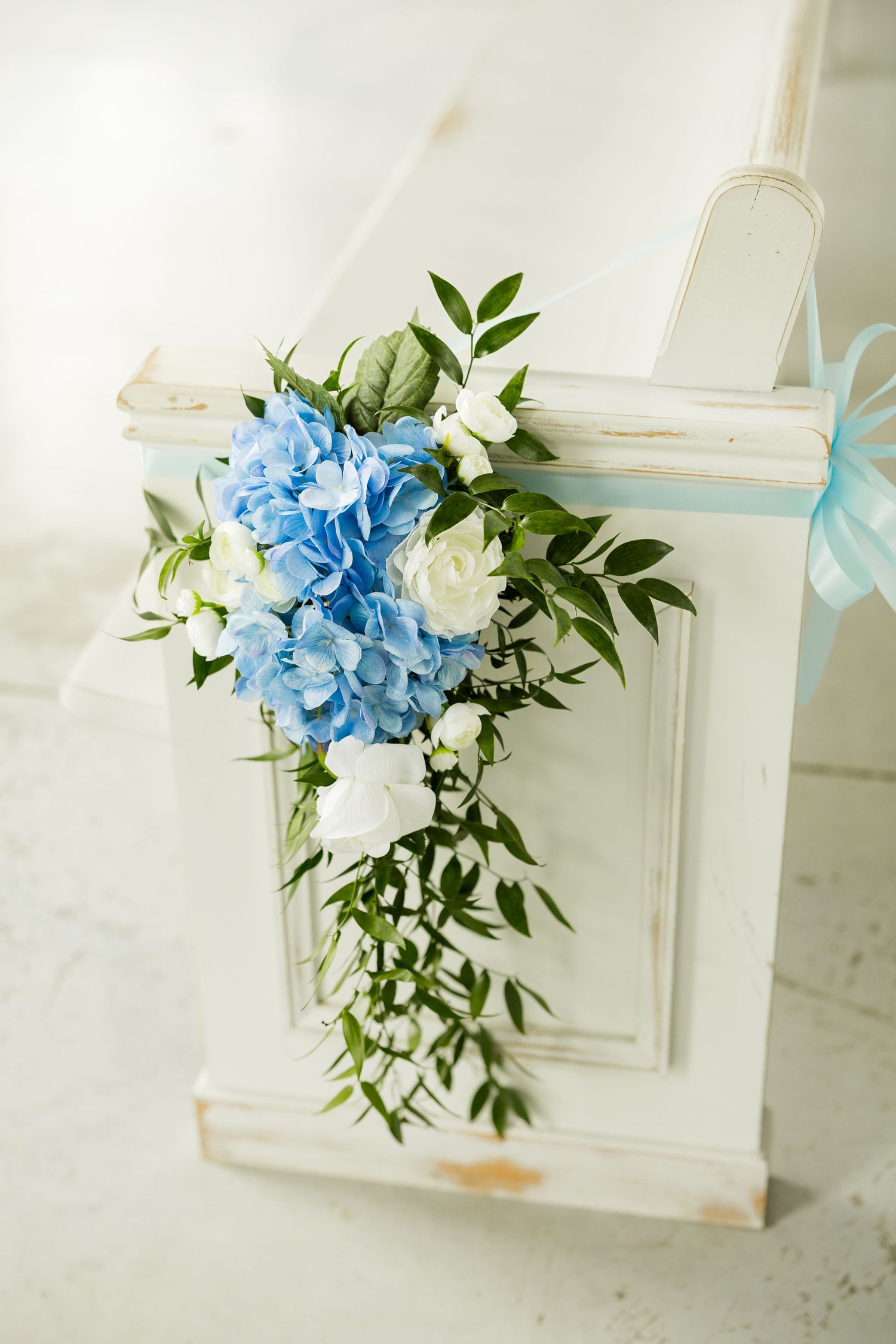 Blue hydrangea and white floral arrangements with greenery decorate a window frame. Cold Springs Events.
