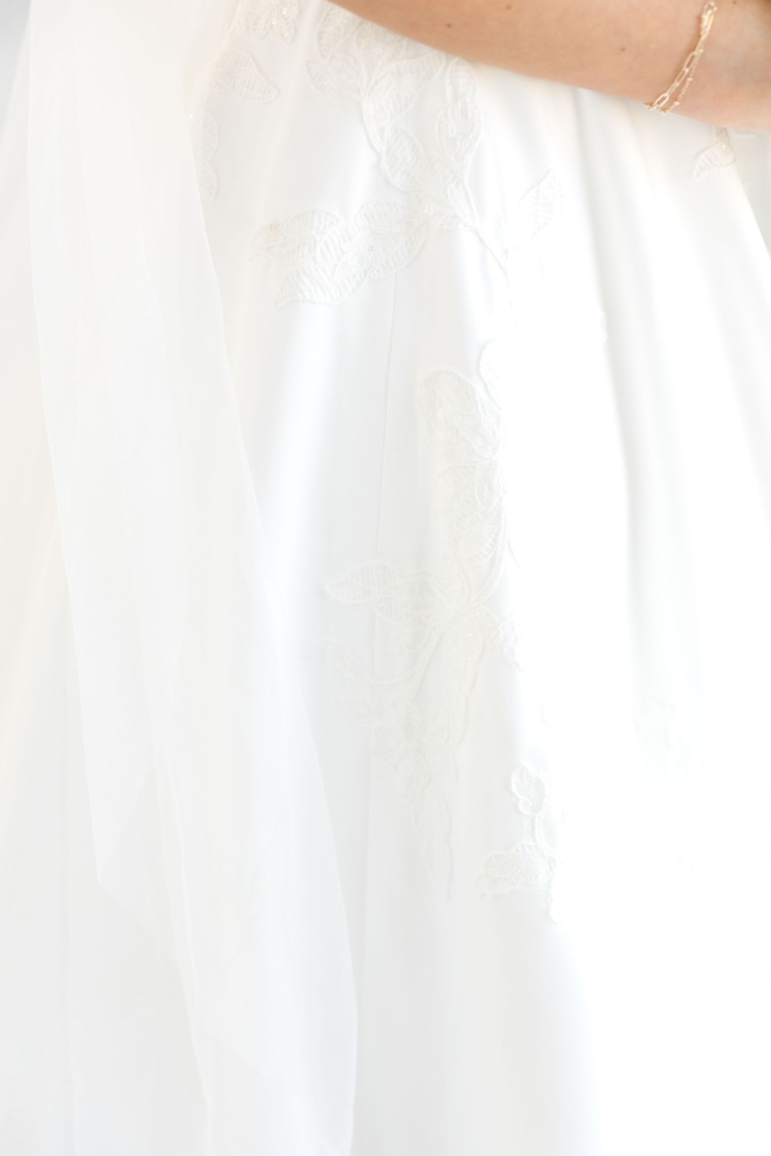 Close-up detail of white wedding dress fabric and delicate trim.