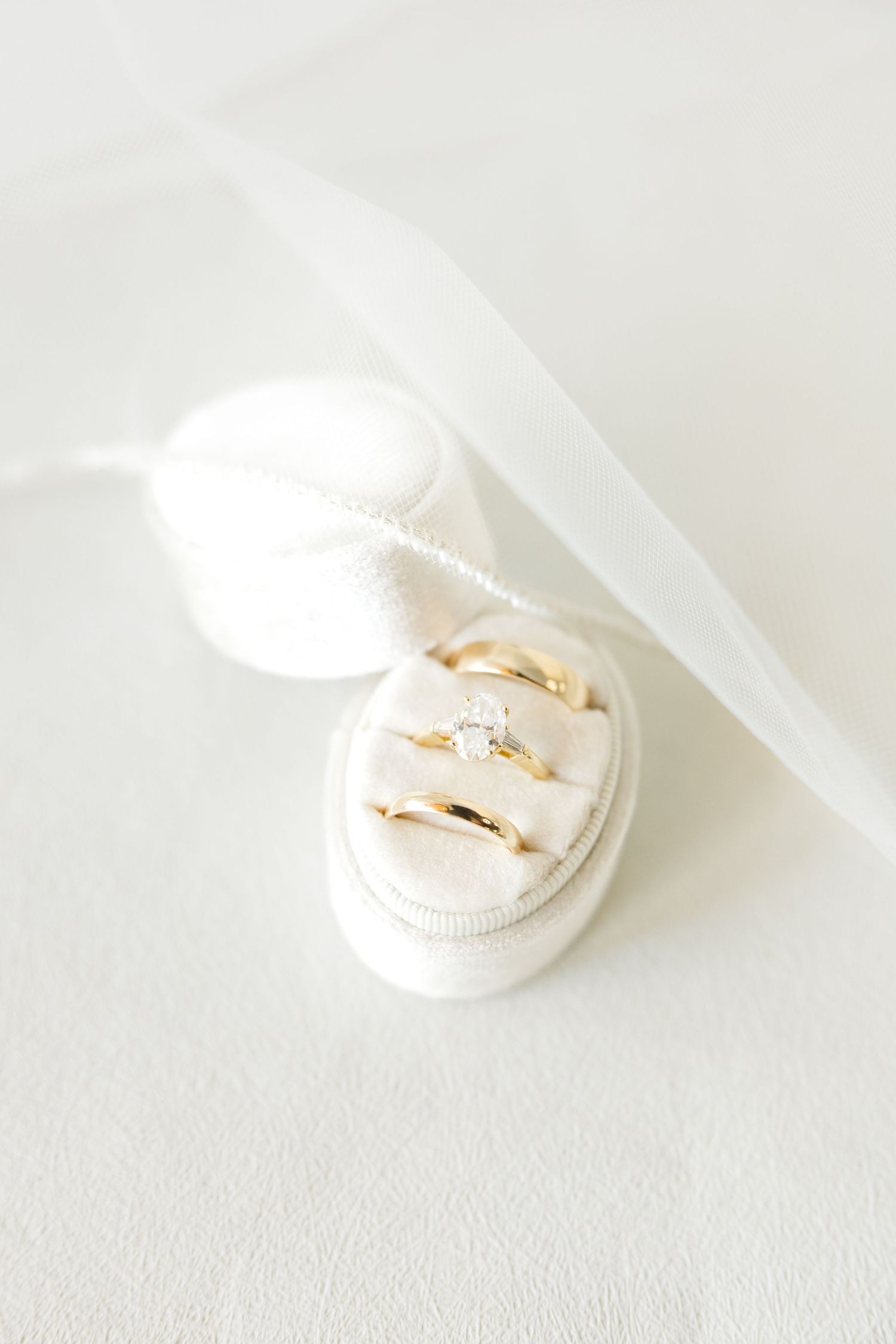 Delicate white silk ribbon gracefully curls and drapes around a small round jewelry box on a light surface.