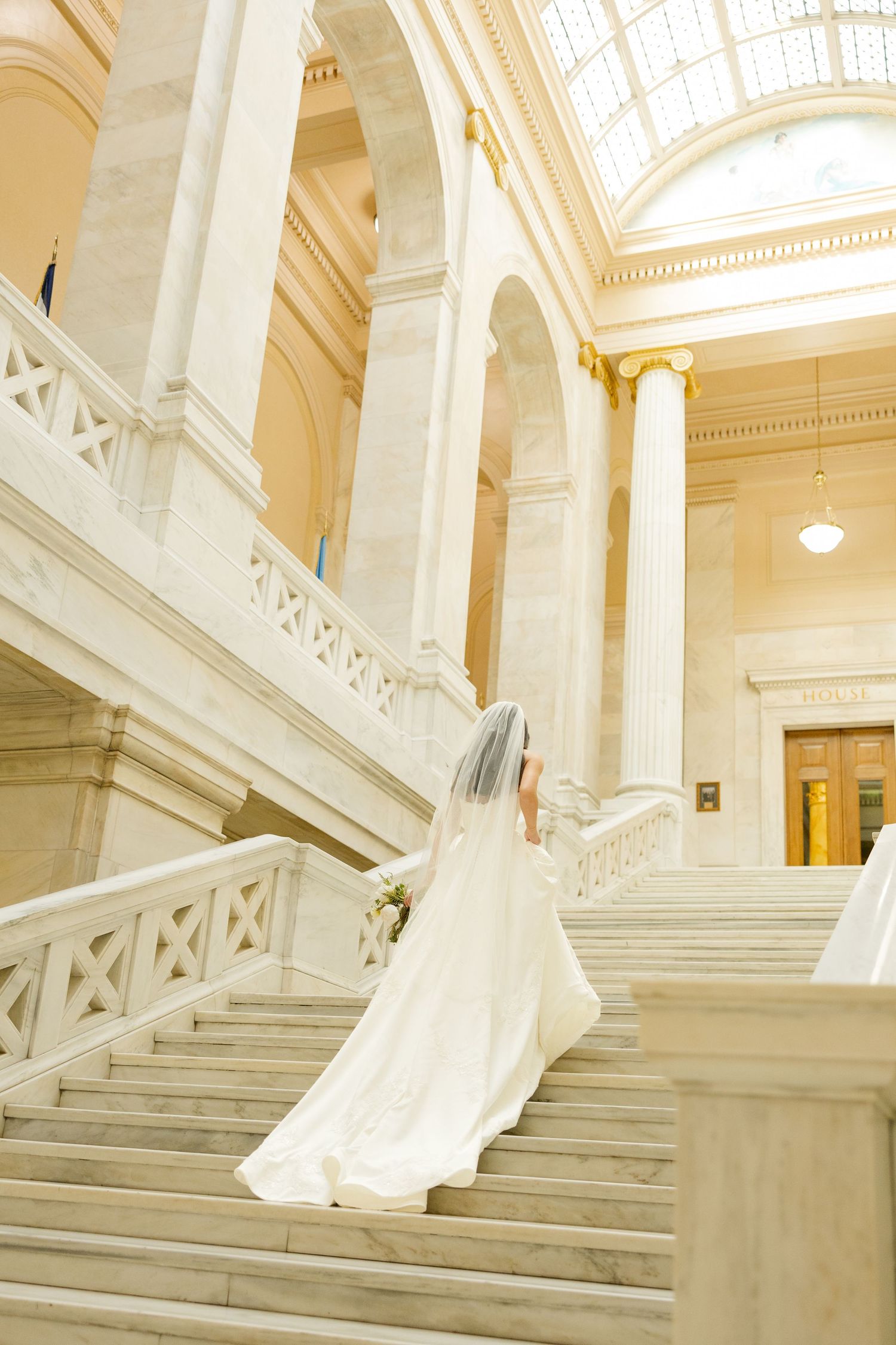 Elegant marble staircase with white columns and ornate architectural details in a grand building interior.