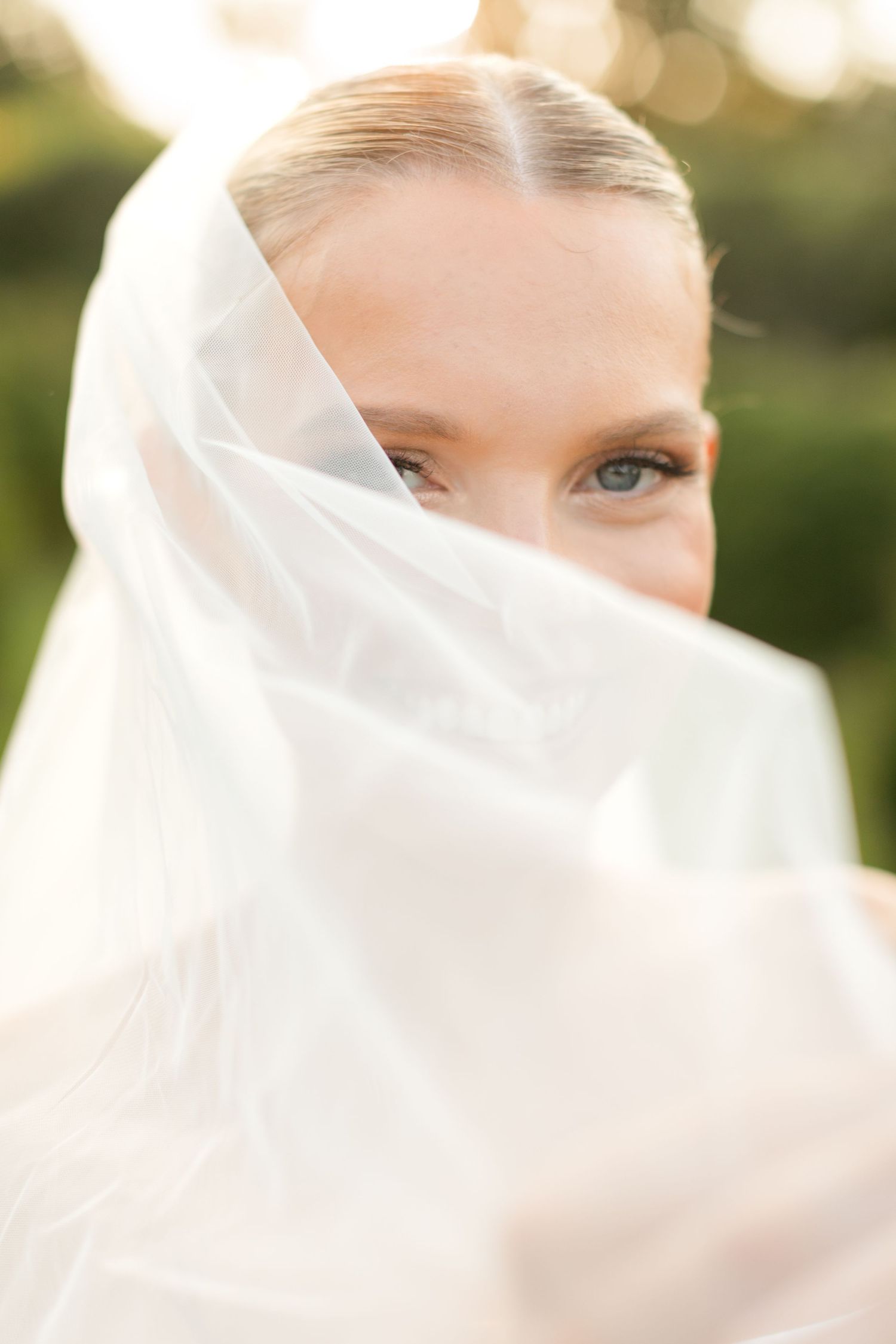 A delicate white bridal veil flows in the breeze, creating an ethereal and romantic wedding portrait.
